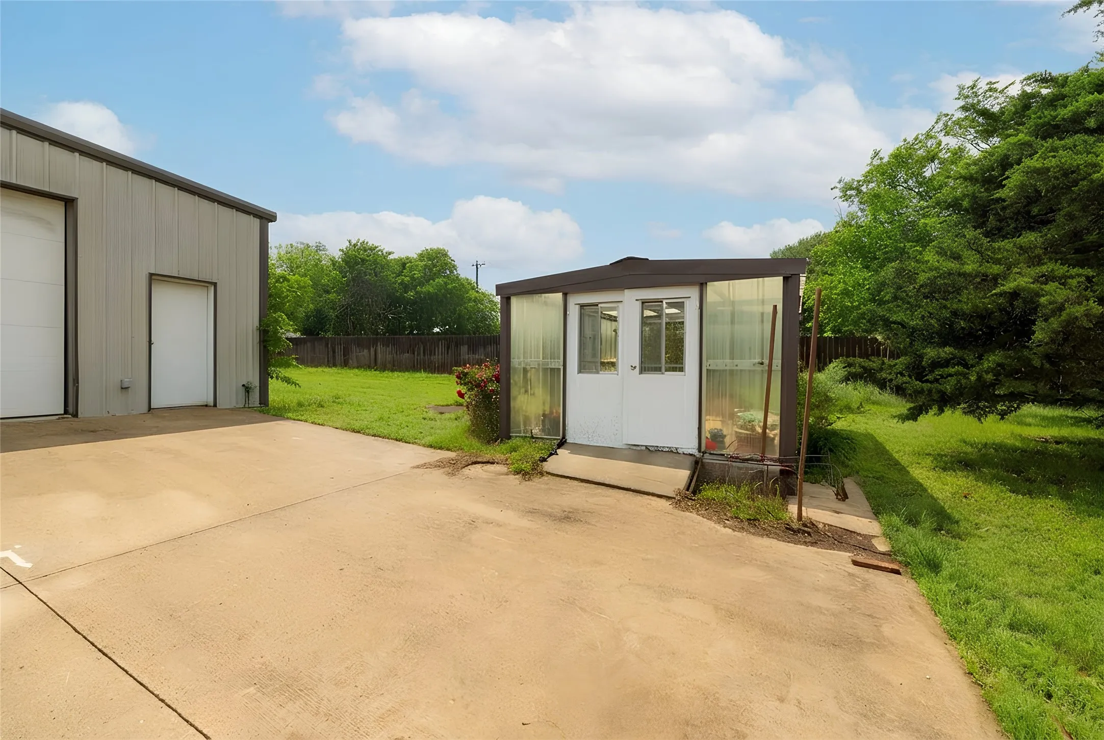 Concrete paved area featuring a metal outbuilding with two roll-up doors and an entry door