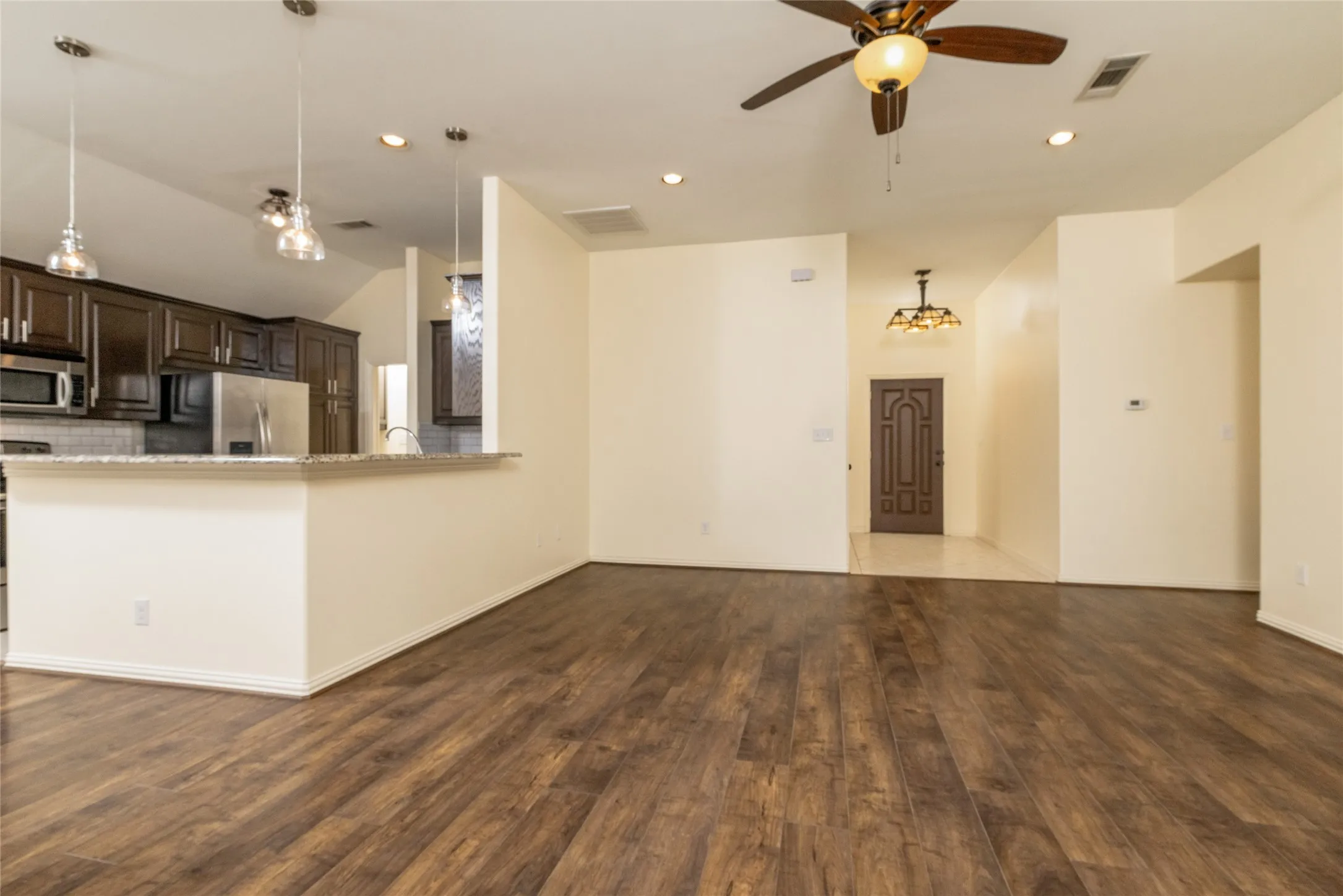 Open-concept living space featuring wood-finish flooring, recessed lighting, and a ceiling fan