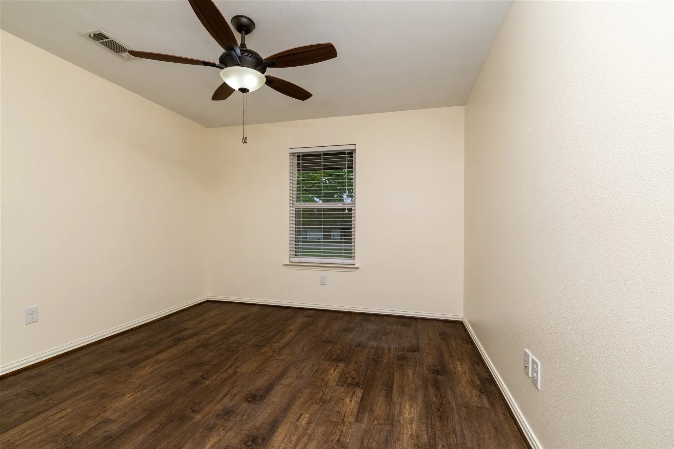Interior room featuring wood-finish flooring, a window with blinds, a ceiling fan with integrated lighting, and neutral-toned textured walls