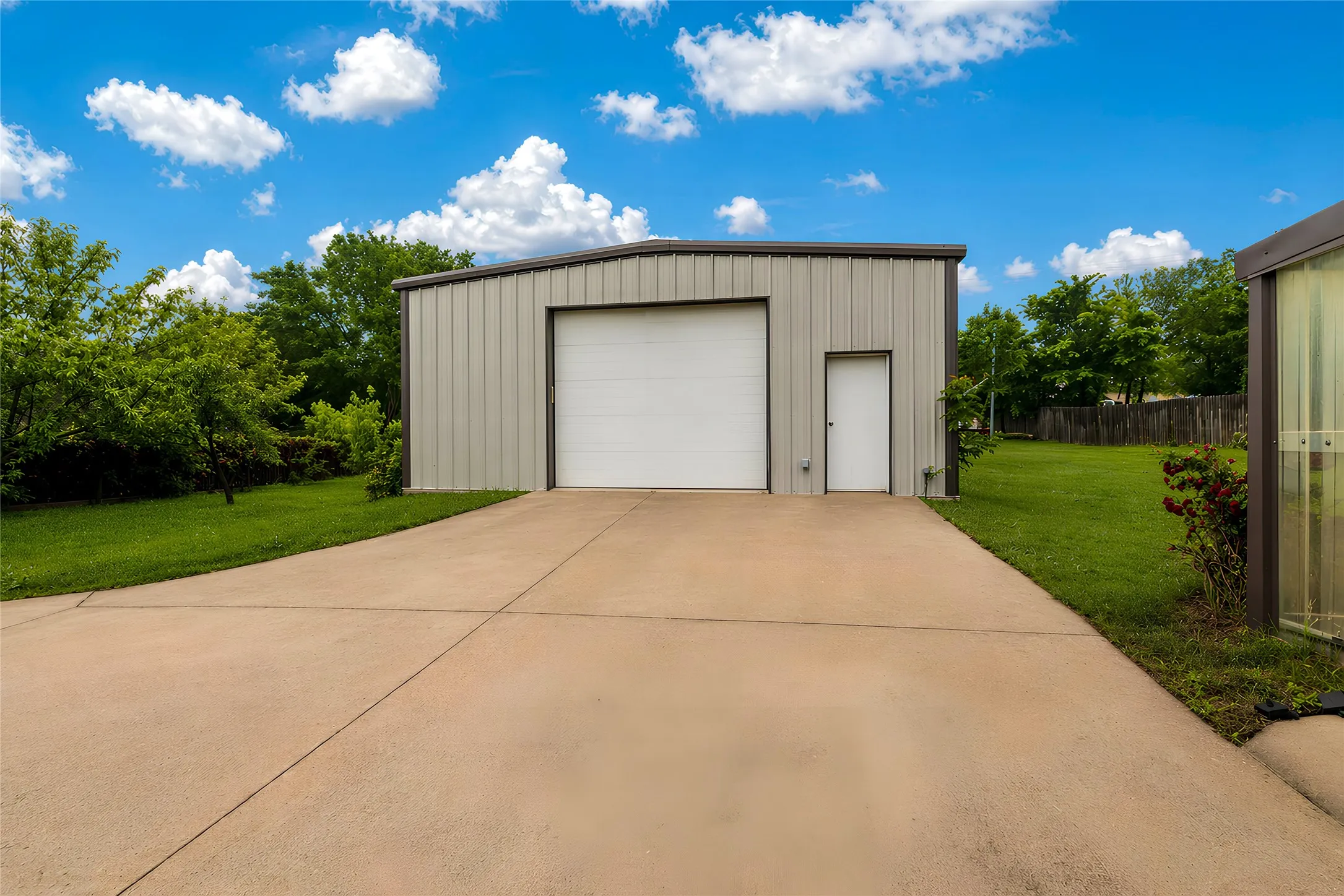Metal-sided utility building featuring a large roll-up door and a separate entry door