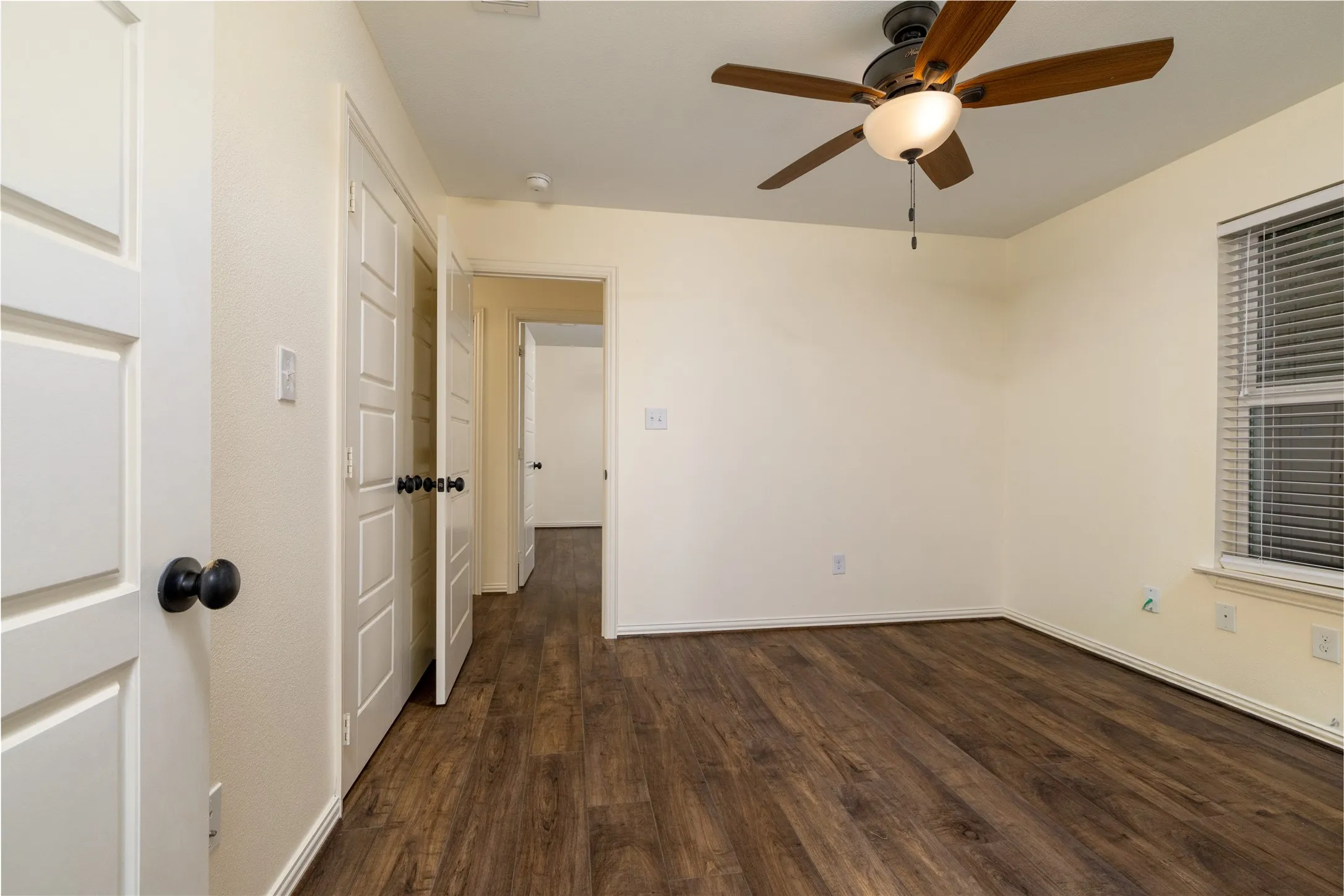 Room featuring wood-finish flooring, light-toned walls, and a ceiling fan with integrated lighting