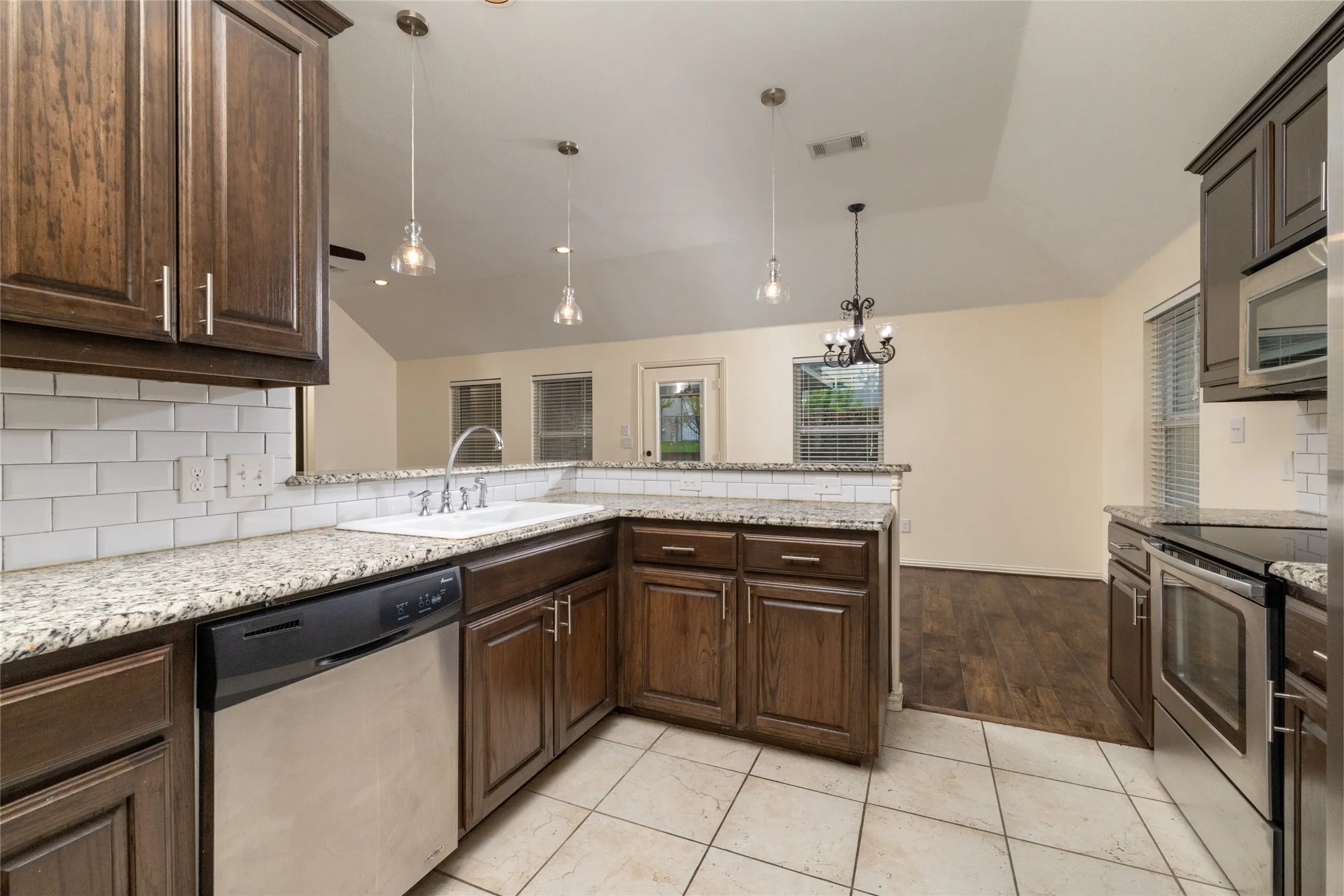 Kitchen featuring granite countertops, a white subway tile backsplash, stainless steel appliances, and dark wood cabinetry