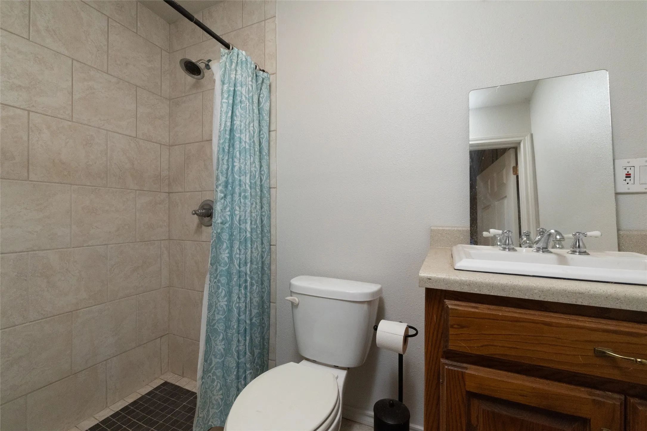 Bathroom featuring a shower with light-toned rectangular wall tiles and darker square floor tiles