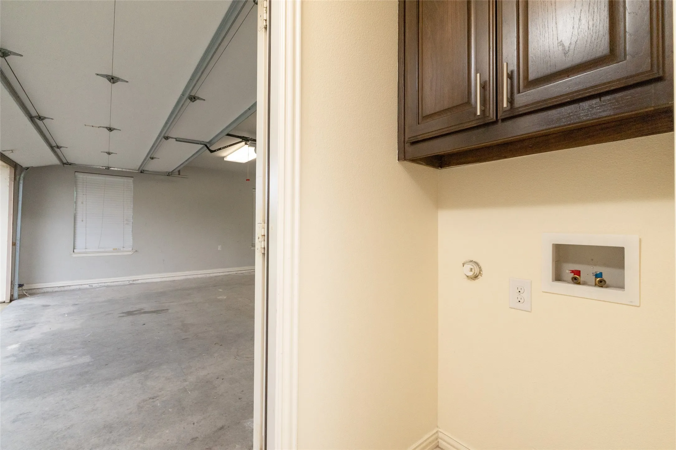 Utility area featuring dark wood-finish cabinetry with silver hardware, and a laundry hookup station