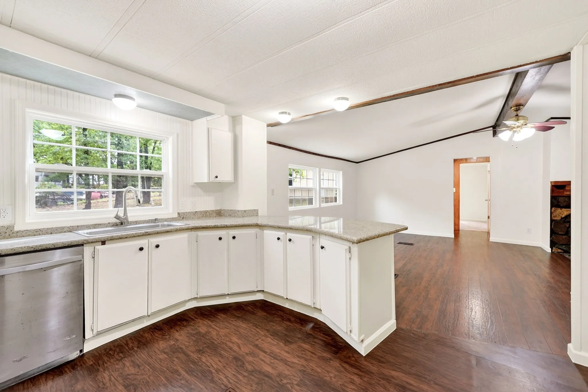 Kitchen featuring white cabinetry, stone-finish countertops, stainless steel dishwasher, and wood-finish flooring