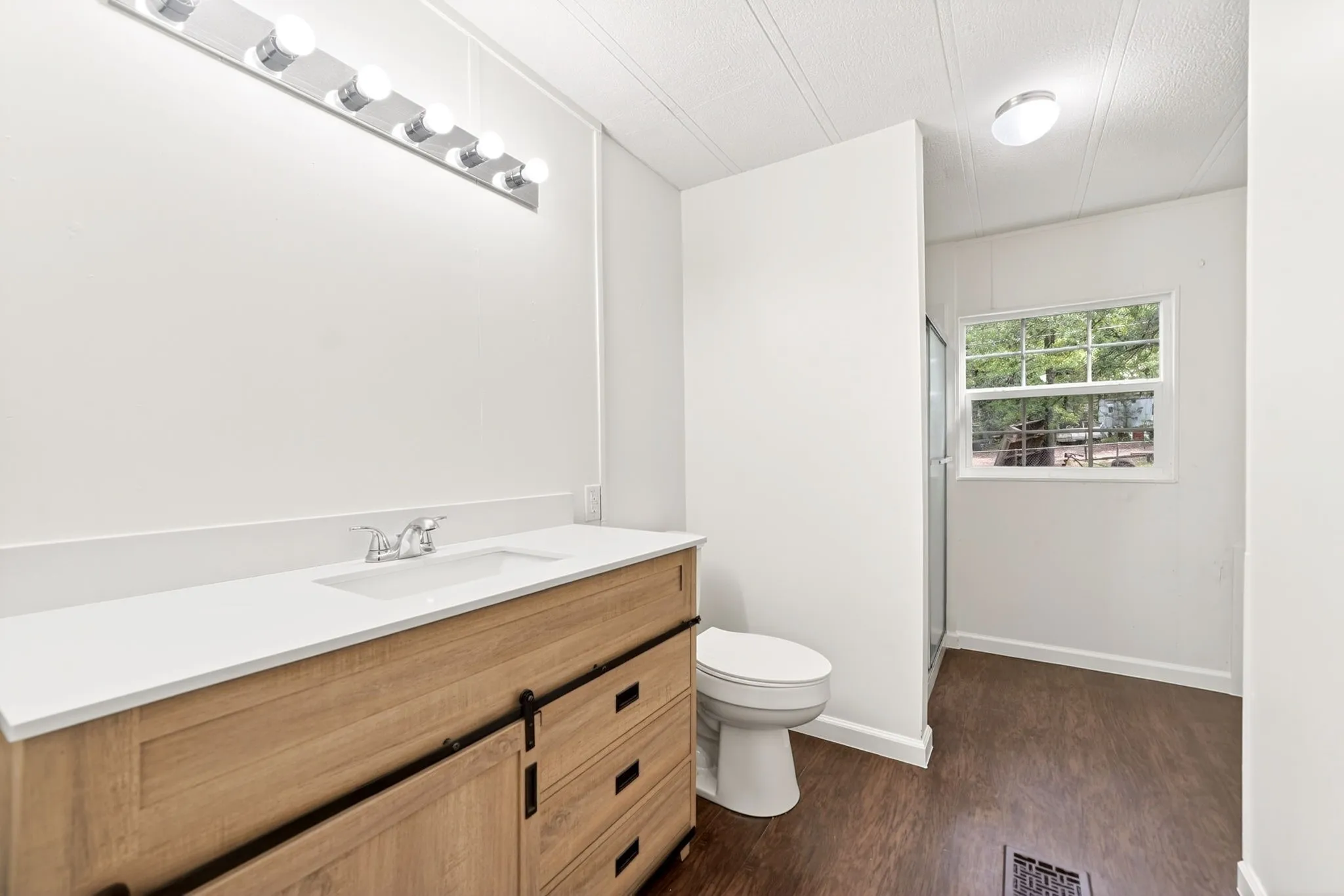 Bathroom vanity featuring a light wood-finish base, white countertop with an integrated sink, and chrome fixtures