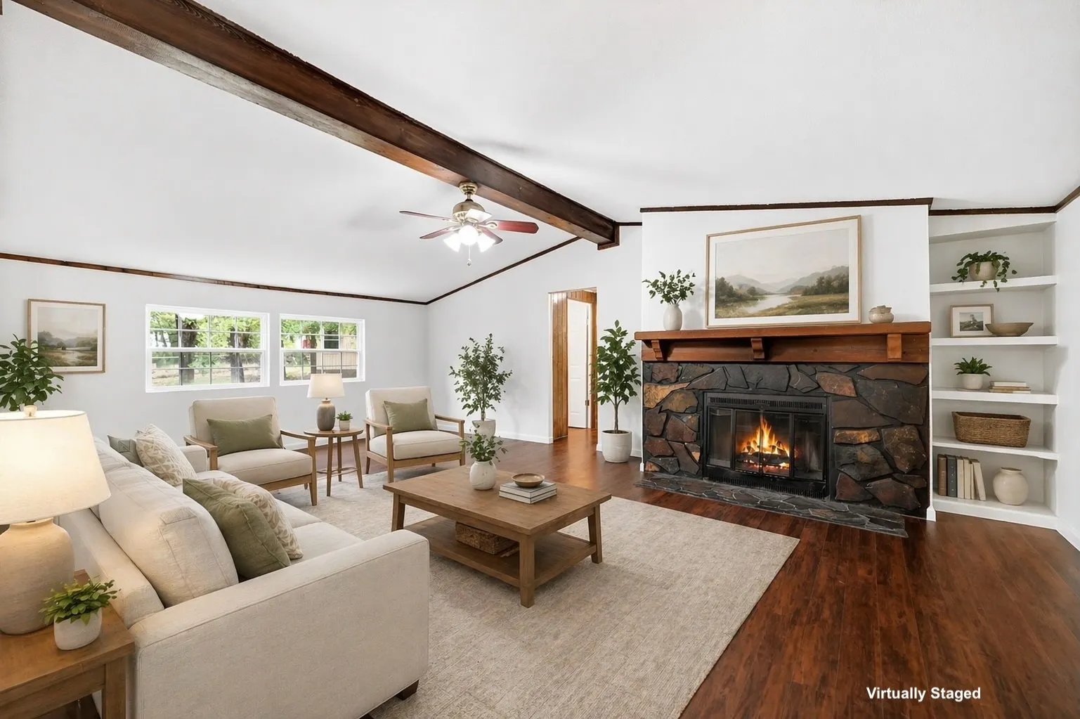 Living area featuring a stone-faced fireplace with a wood mantel, built-in shelving, vaulted ceilings with exposed wood beams, wood-finish flooring, and multiple windows providing natural light