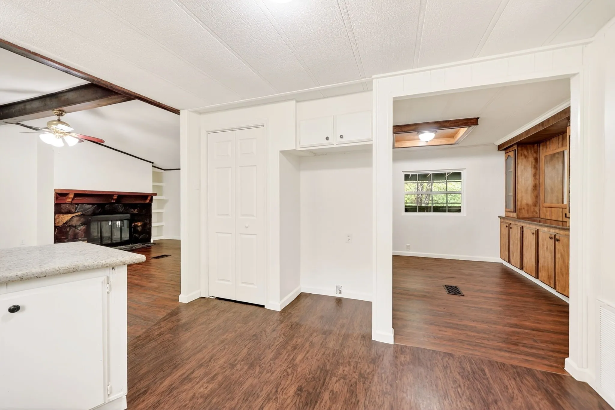 Interior space featuring wood-finish flooring throughout, a white kitchen island with a light-toned countertop, and white cabinetry