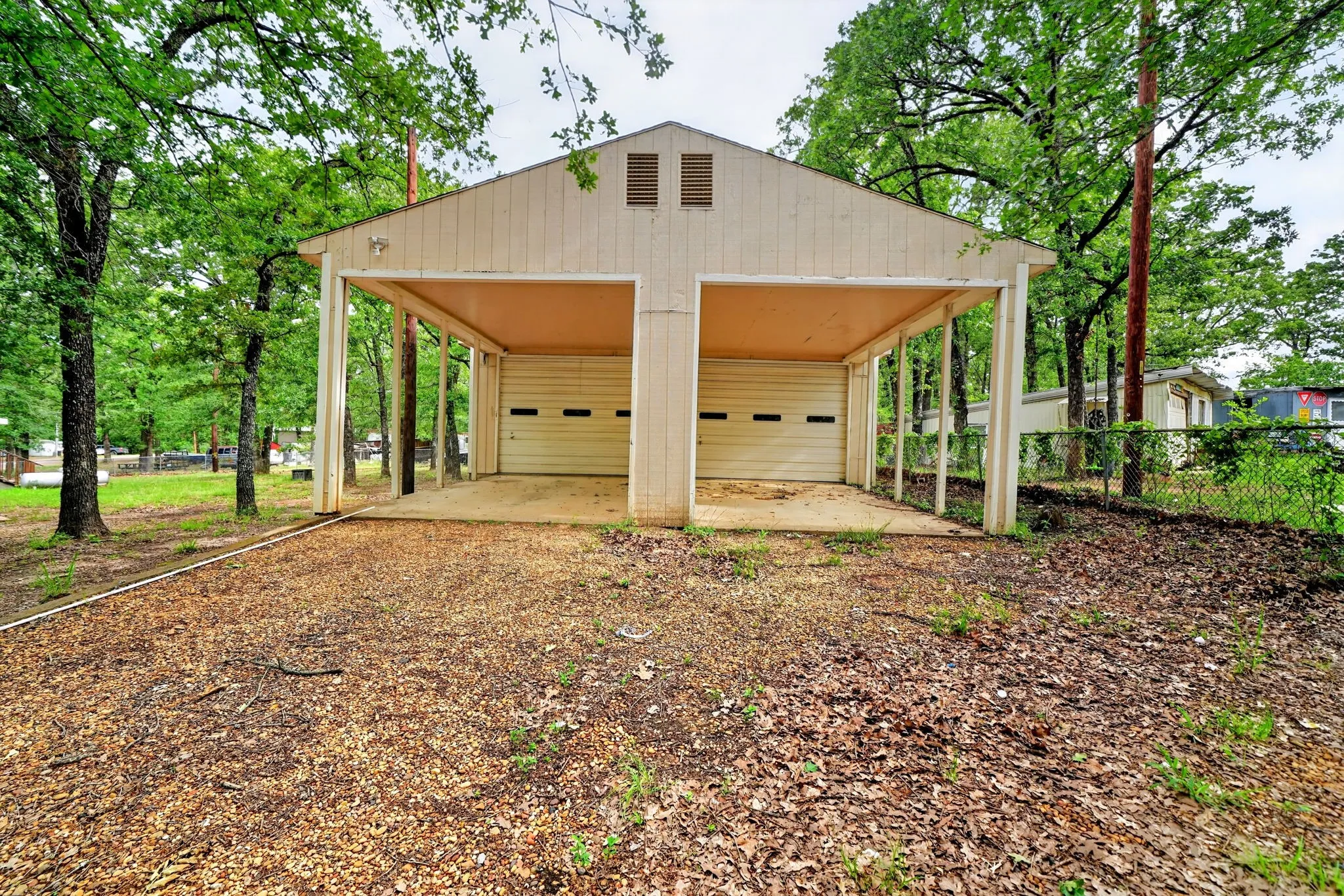 Two-bay garage structure featuring light-toned siding and two roll-up garage doors