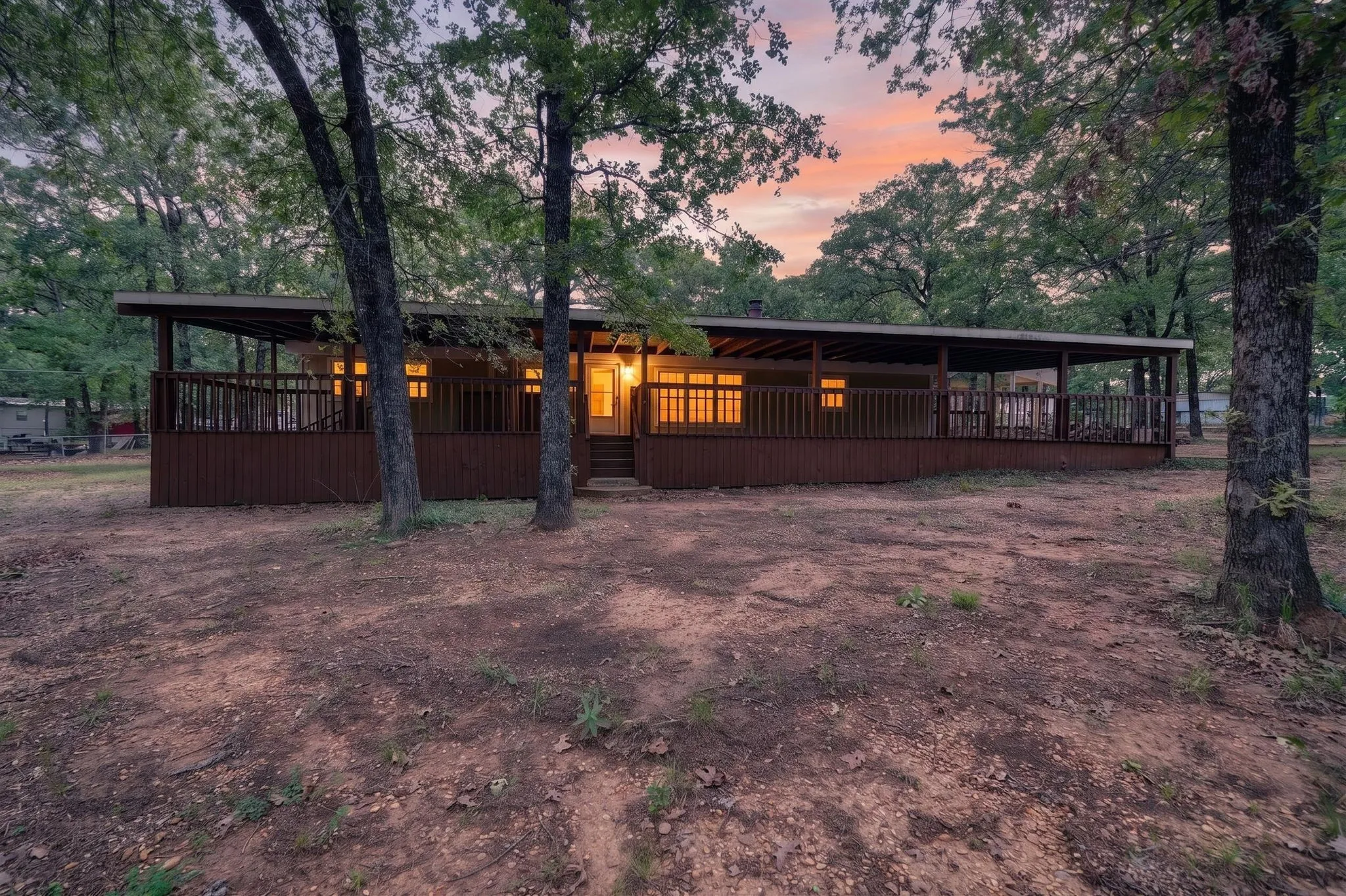 Single-story residence featuring a full-length covered porch with railing, wood siding, and multiple windows