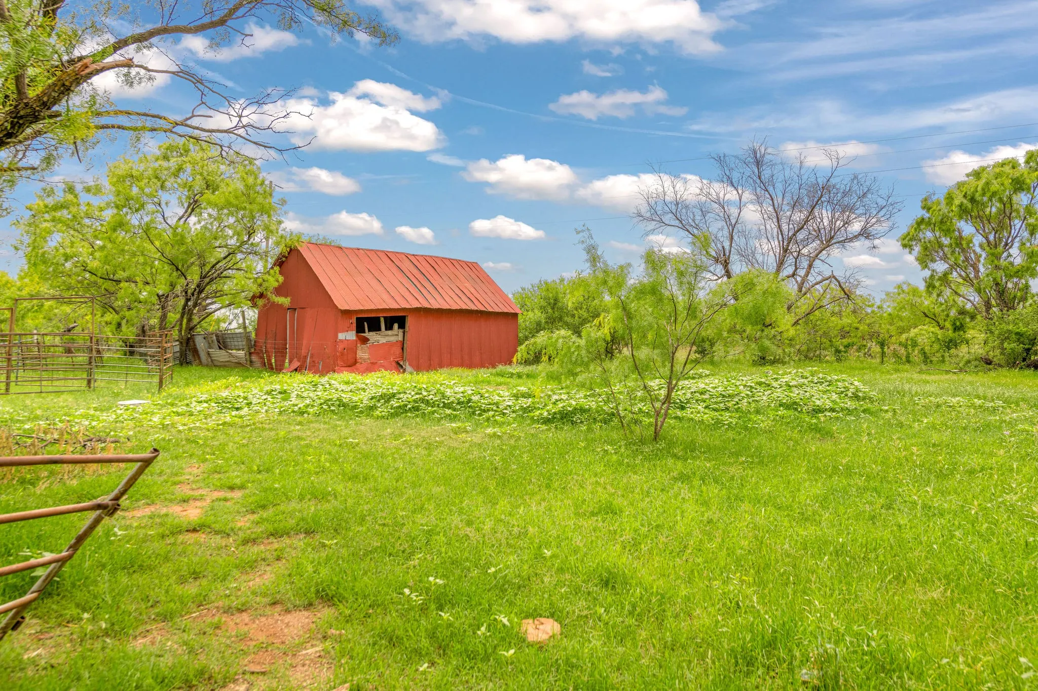 Red barn with a metal roof, cattle panels for catch pen.