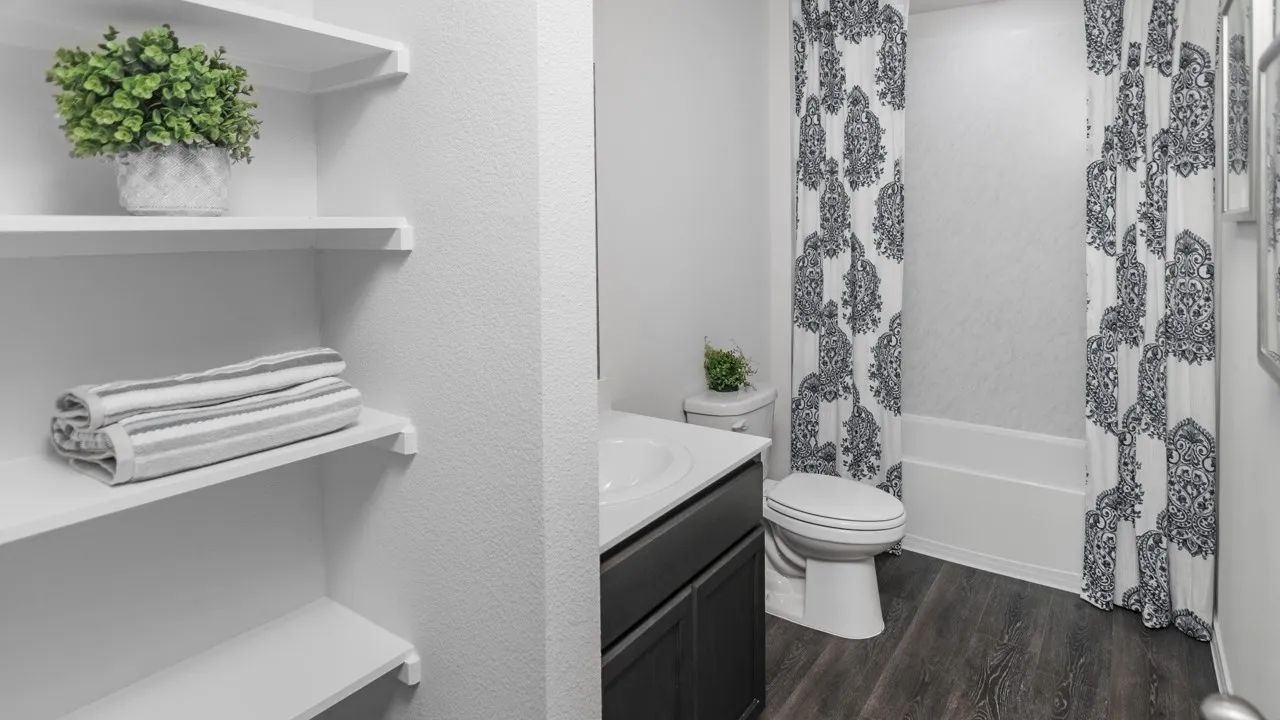Bathroom featuring a white vanity with an integrated sink, dark wood-finish cabinetry, a standard toilet, and a shower-tub combination with a white surround