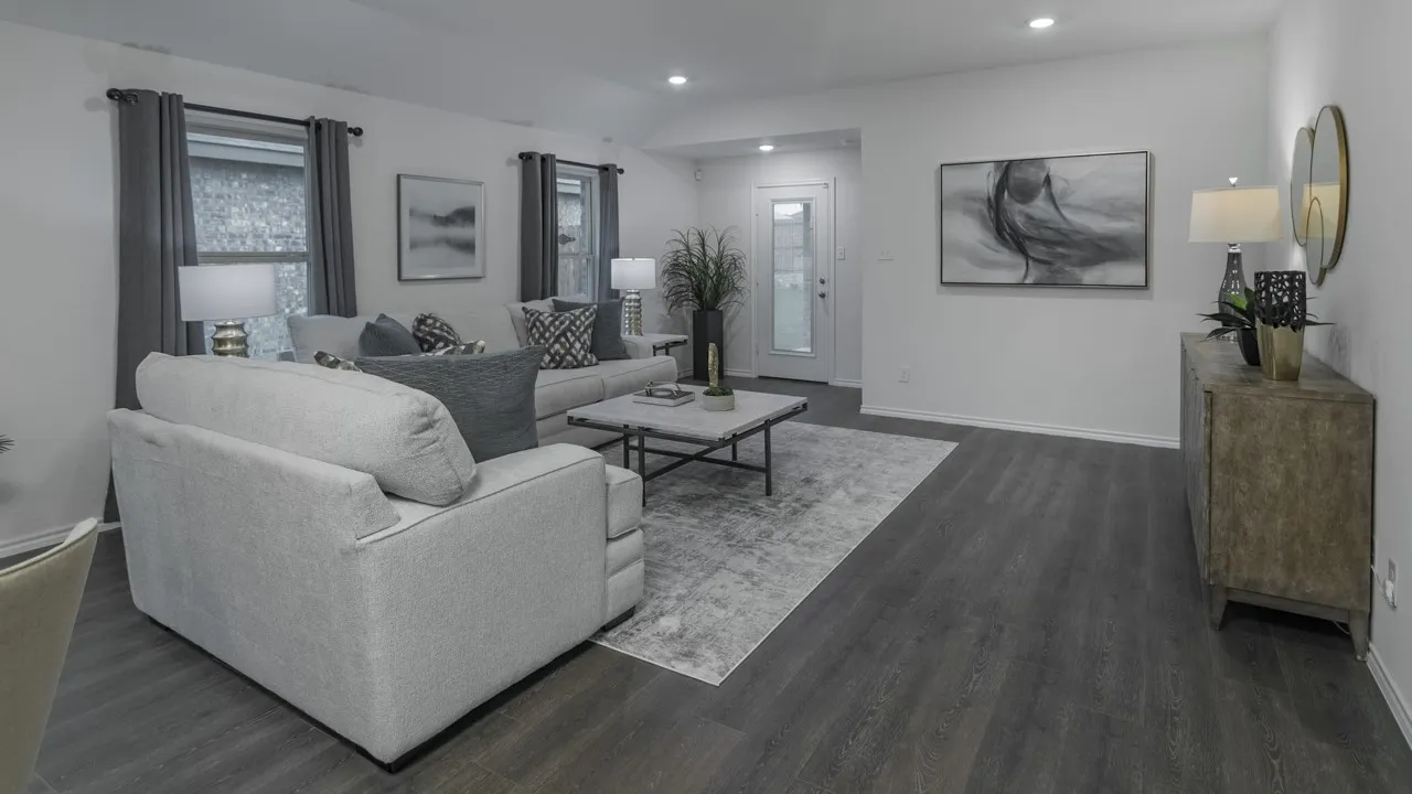 Open-concept living area featuring dark wood-finish flooring, recessed ceiling lighting, and multiple windows with privacy glass