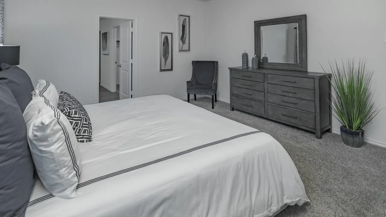 Carpeted bedroom with a single white door, light gray walls, and a recessed ceiling light