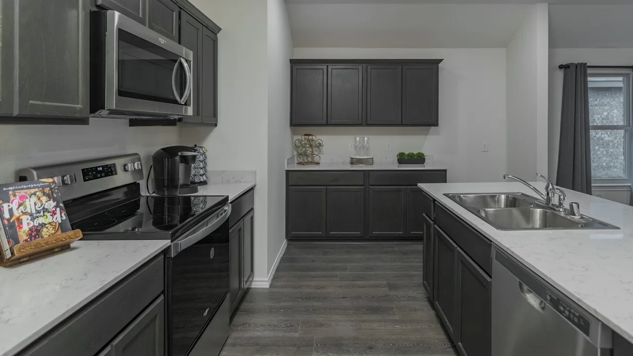 Modern kitchen featuring dark cabinetry, light countertops, wood-finish flooring, stainless steel appliances, and an island with a double basin sink