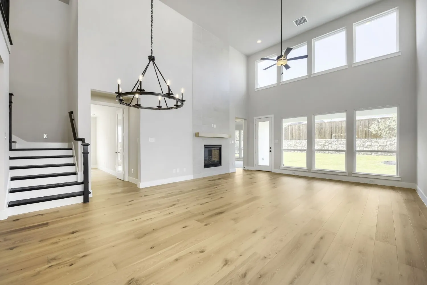 Expansive living space featuring high ceilings, wood-finish flooring, and a contemporary fireplace