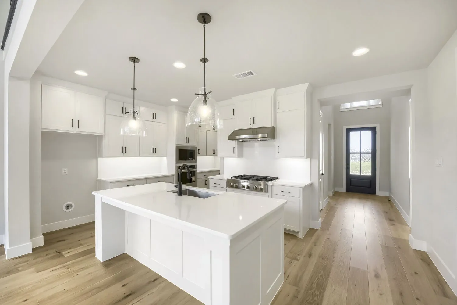 Modern kitchen featuring white cabinetry, quartz countertops, a stainless steel gas range, and wood-finish flooring