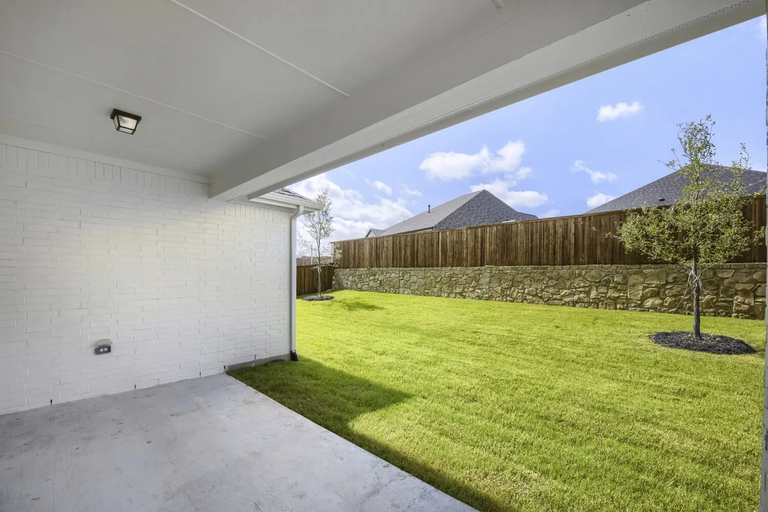 Covered concrete patio with a white painted brick exterior wall