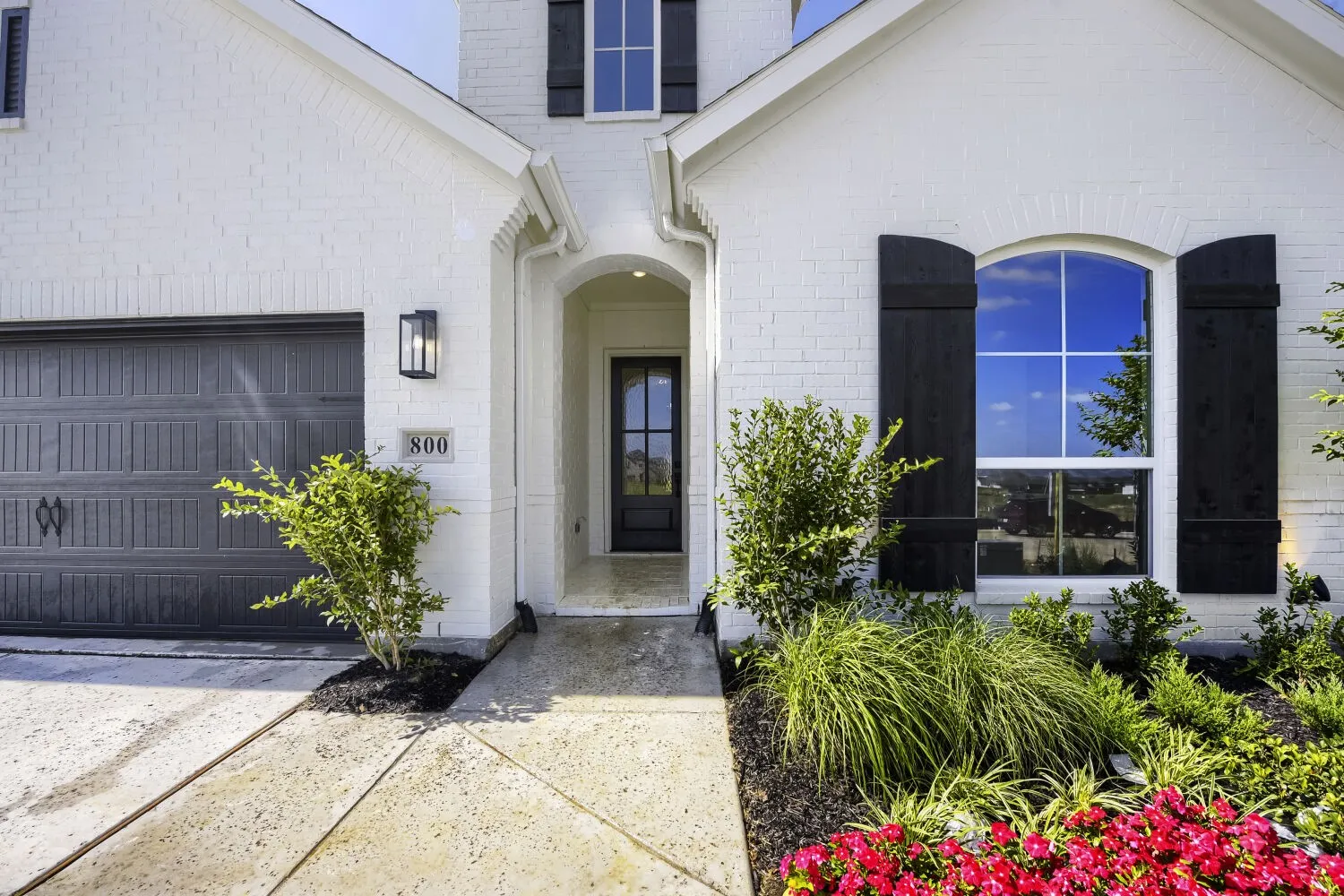 White brick exterior with black shutters and a complementary dark garage door