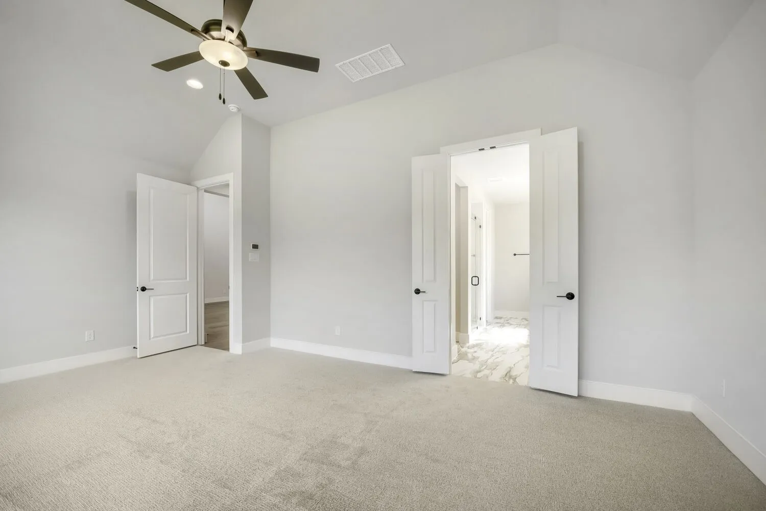 Spacious room featuring vaulted ceilings, light-toned carpeting, and a ceiling fan with integrated lighting