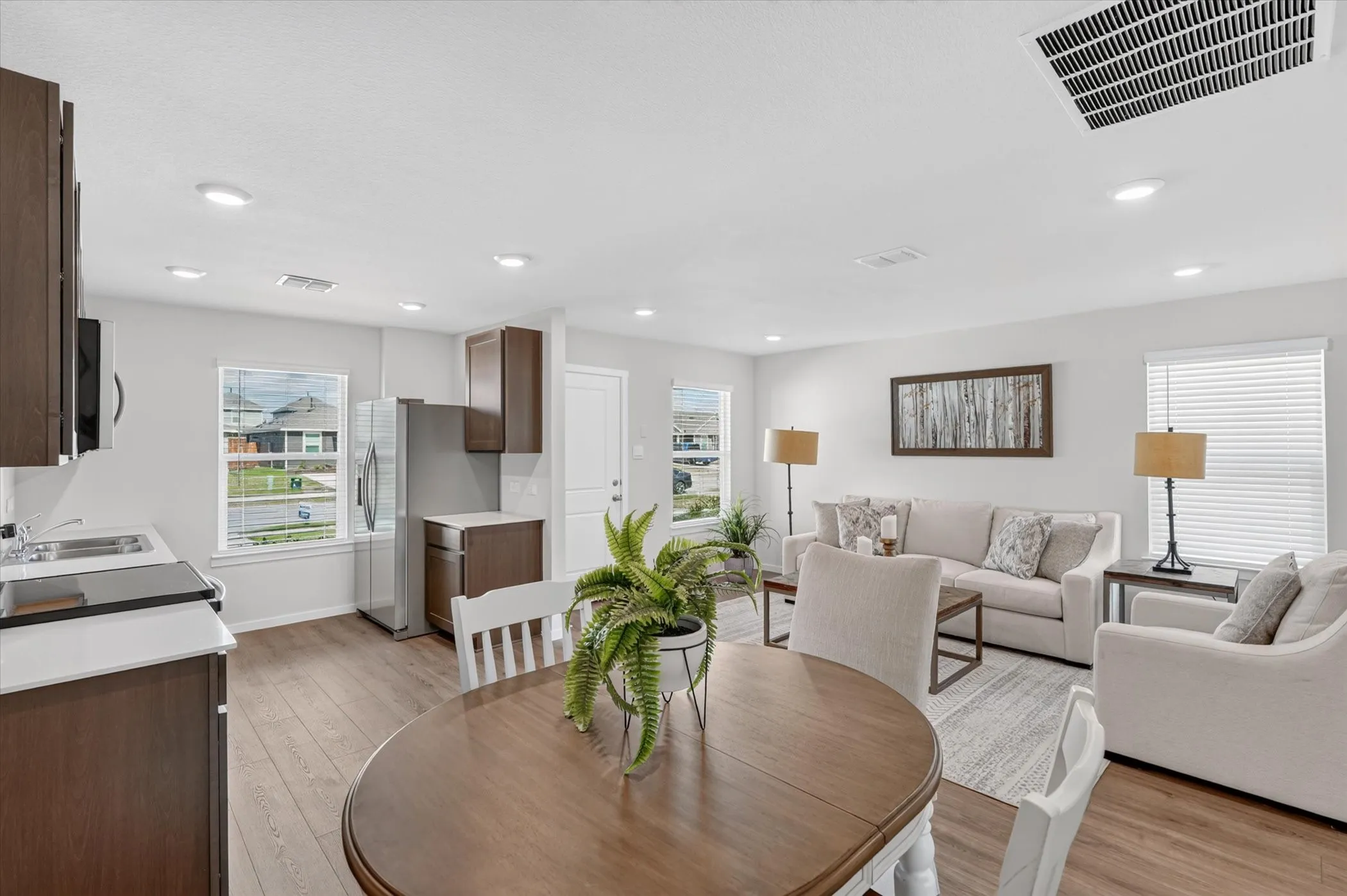 Open concept living area featuring wood-finish flooring, recessed lighting, white walls, and dark wood-tone cabinetry
