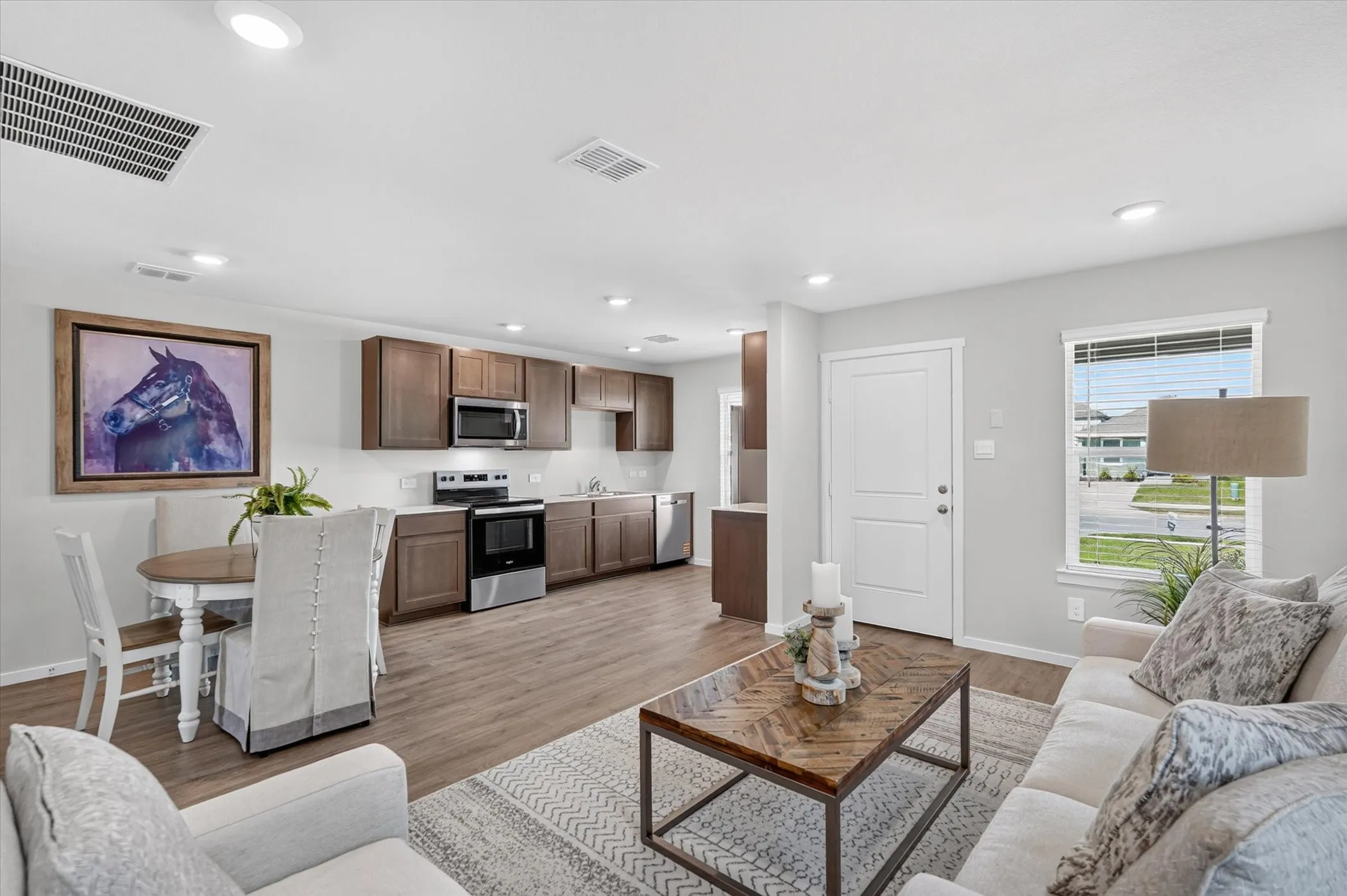 Open-concept living space featuring wood-finish flooring, recessed lighting, and a kitchen with stainless steel appliances