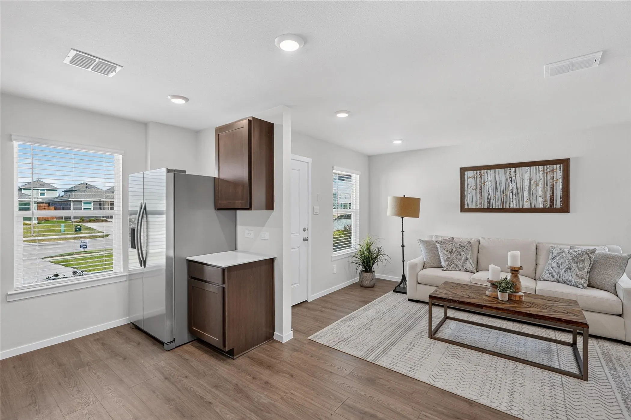 Open-concept living space with wood-finish flooring, recessed lighting, and white walls