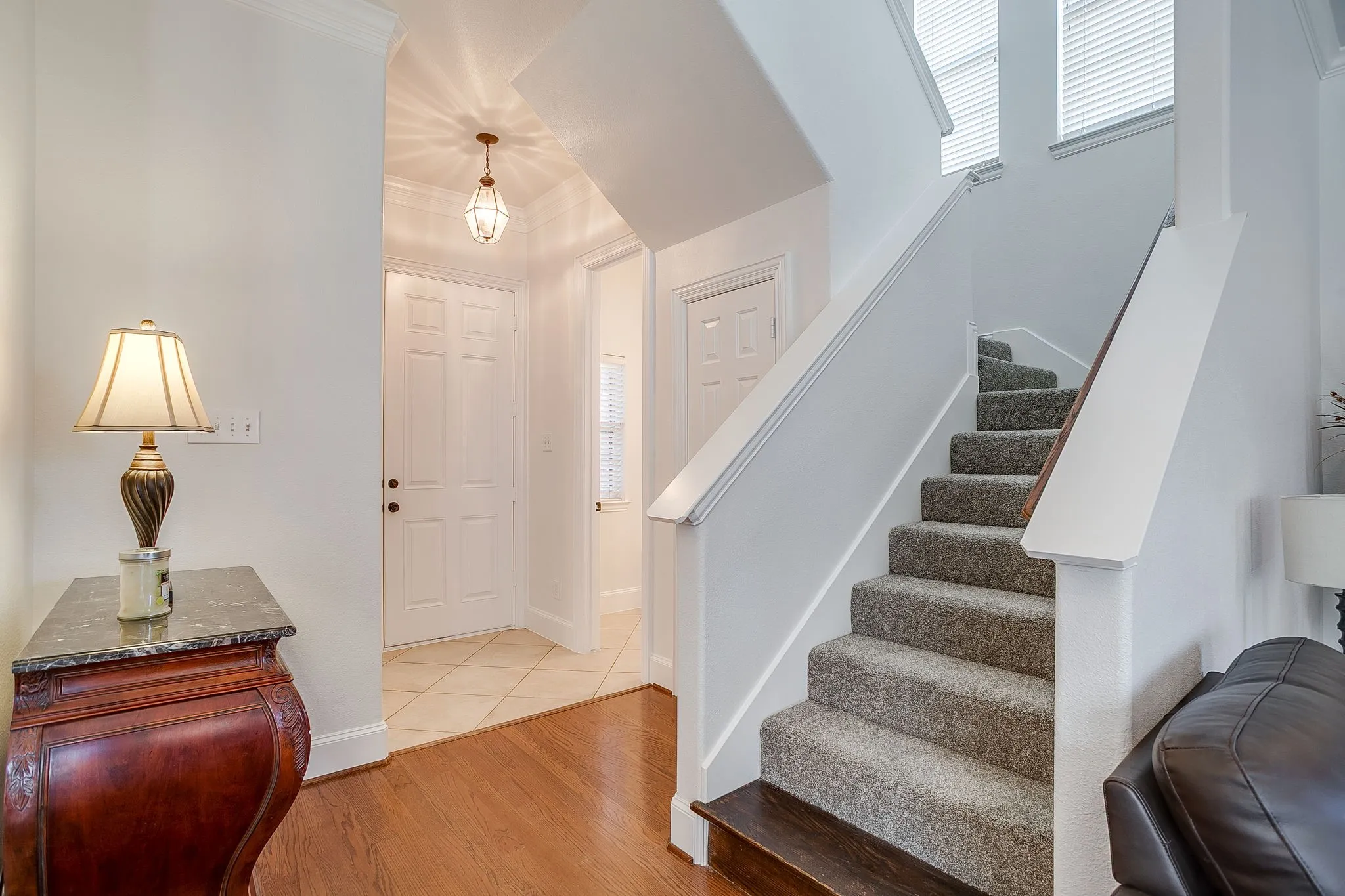 Foyer featuring light wood finished floors, ornamental molding, and stairs