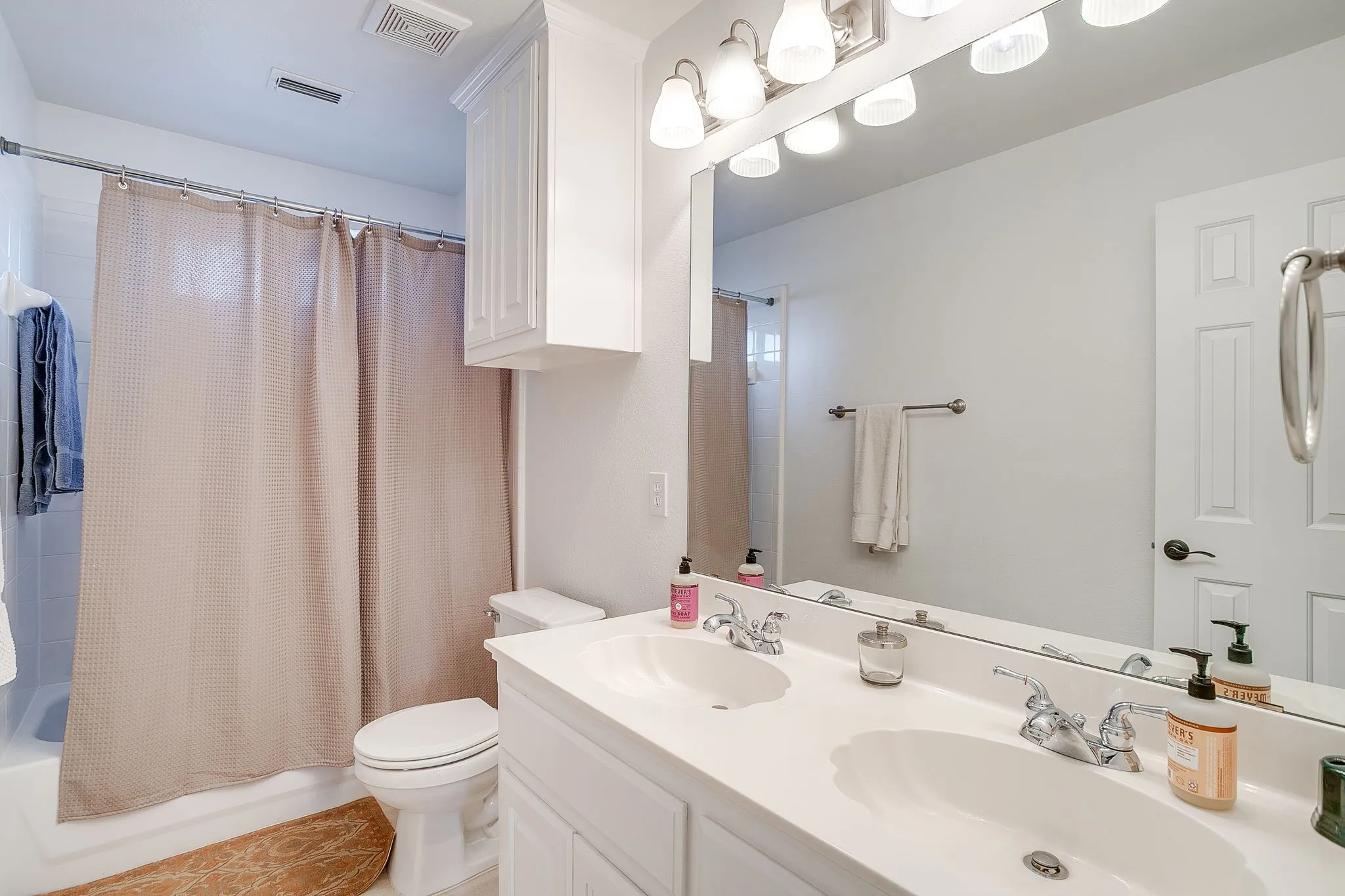 Full bathroom with shower / bath combination with curtain and double vanity
