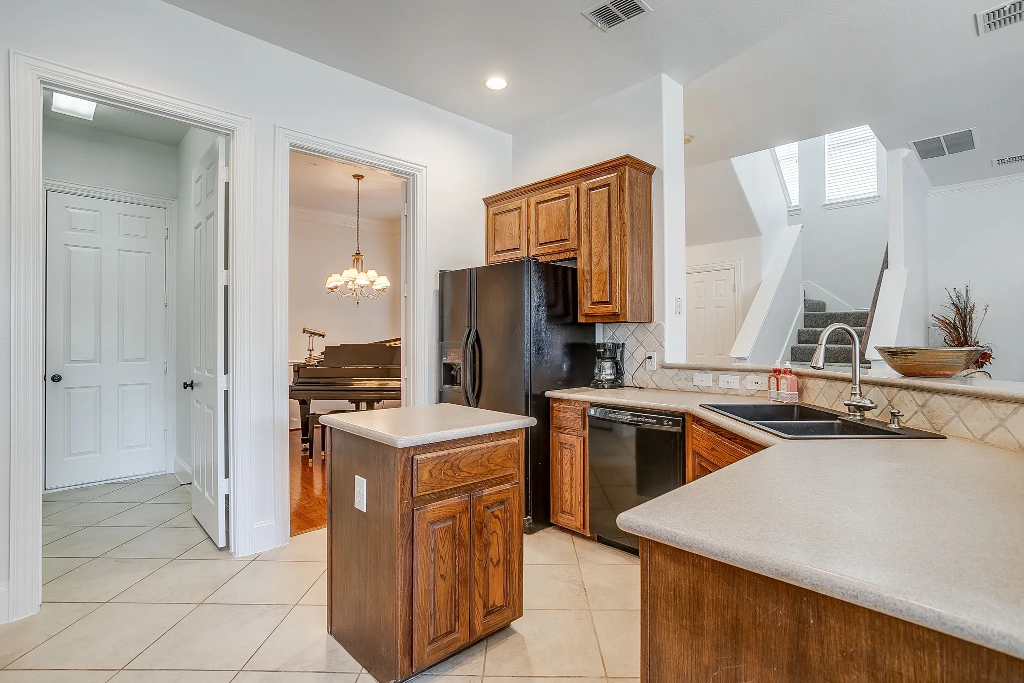 Kitchen featuring a chandelier, brown cabinets, dishwasher, backsplash, and a center island