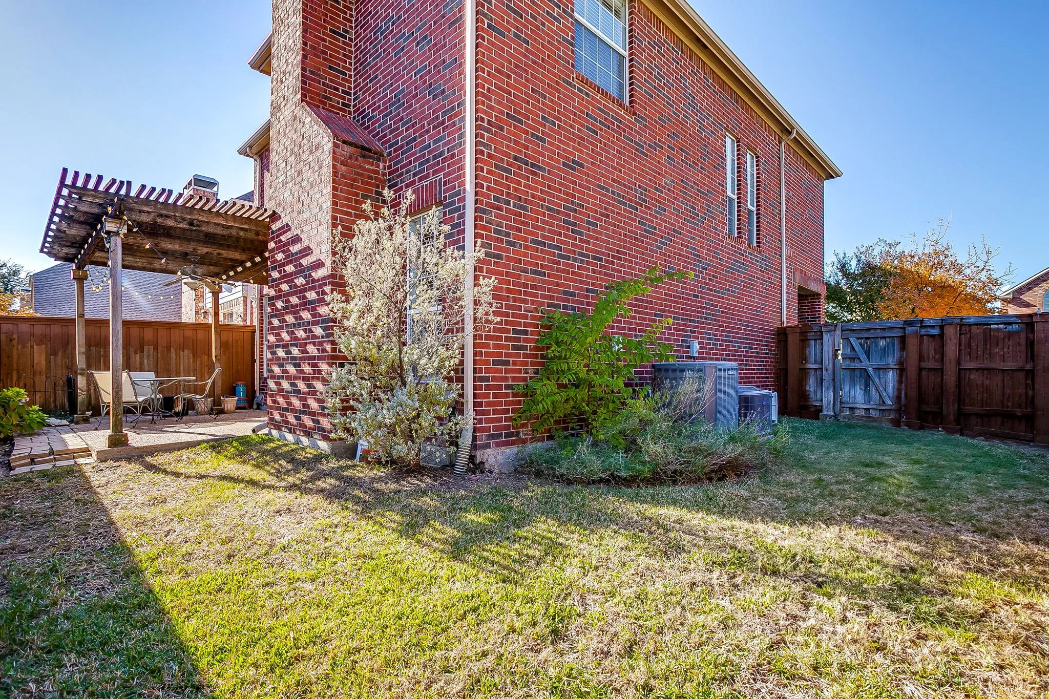 View of home's exterior featuring a fenced backyard, a pergola, brick siding, and a patio