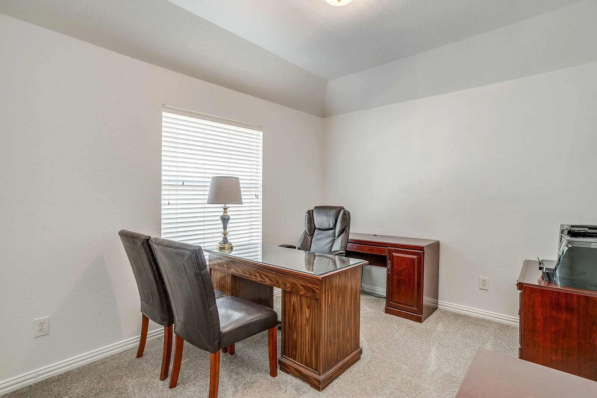 Office with light colored carpet and vaulted ceiling