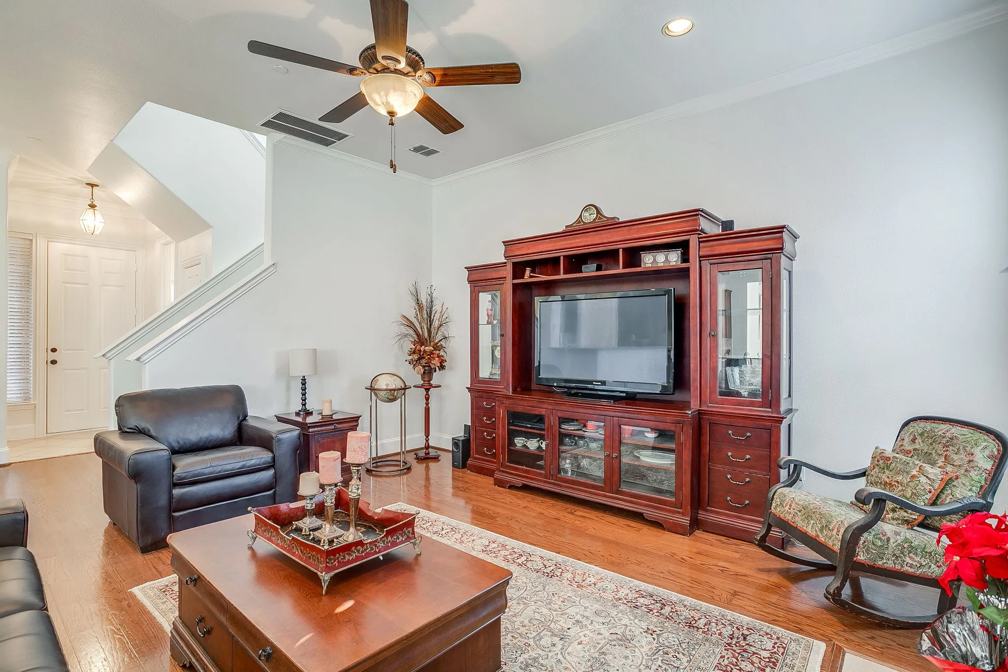 Living room with ornamental molding, light wood-style flooring, a ceiling fan, and stairway