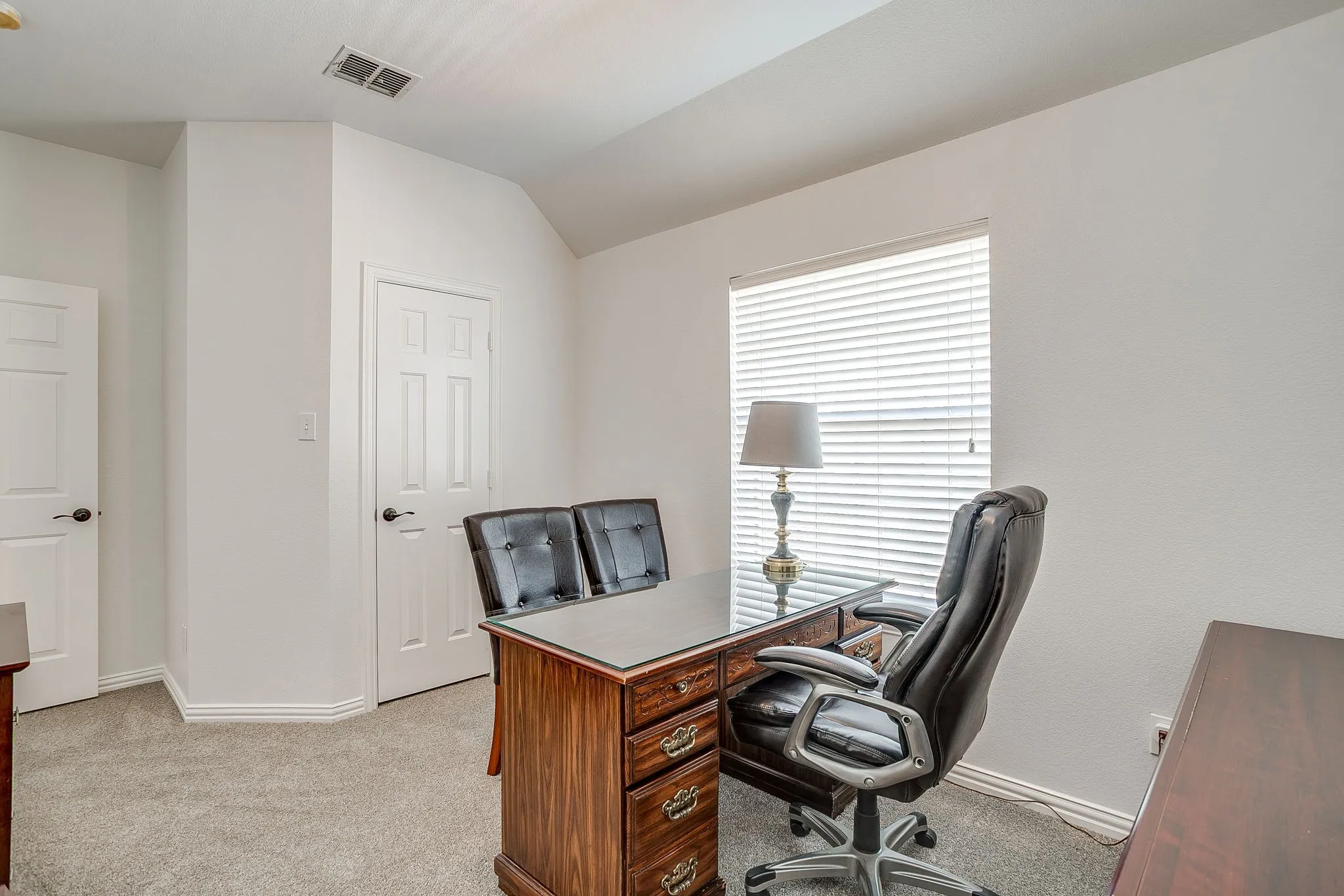 Office with light colored carpet and lofted ceiling