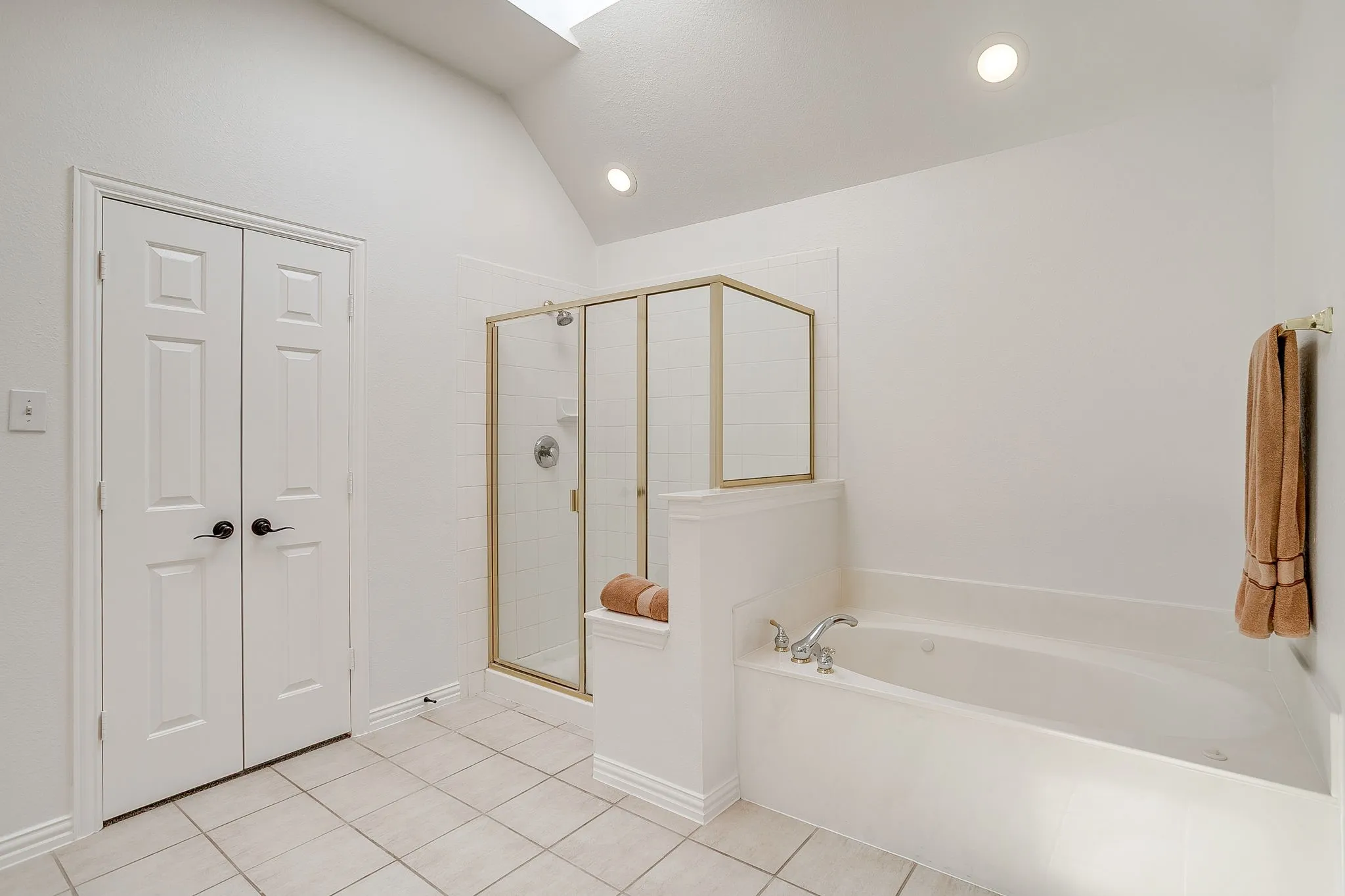 Bathroom featuring a bath, a shower stall, vaulted ceiling, a skylight, and recessed lighting