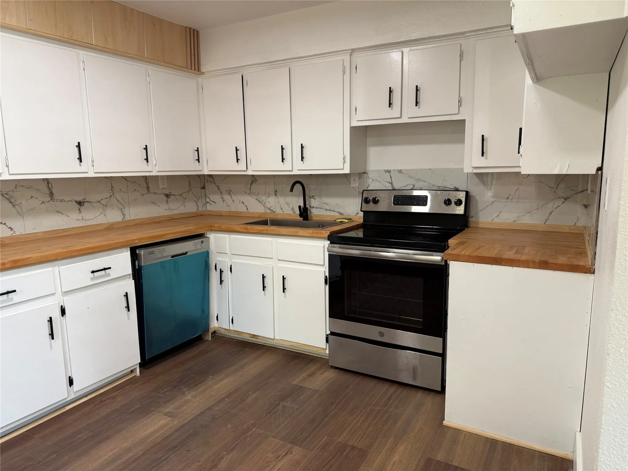 Kitchen featuring white cabinetry, wood-finish countertops, a stainless steel range, and a patterned tile backsplash
