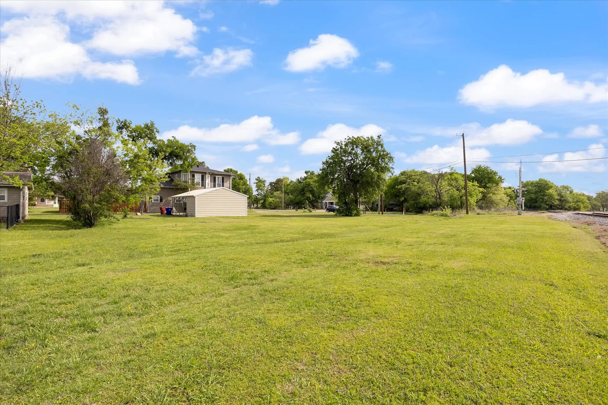 Expansive green lawn with mature trees and a detached shed