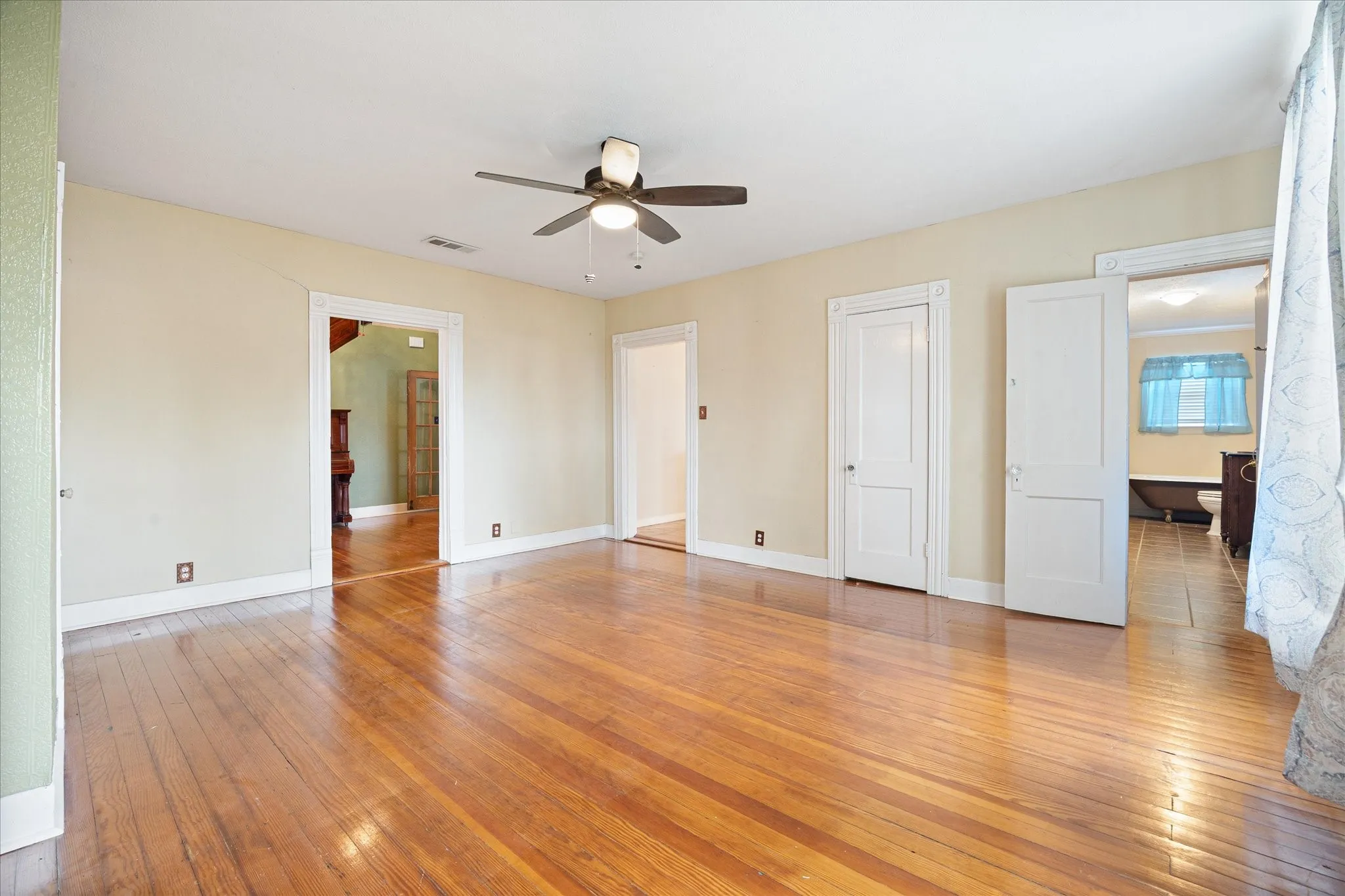 Hardwood flooring throughout featuring a ceiling fan, baseboards, and multiple doorways with trim