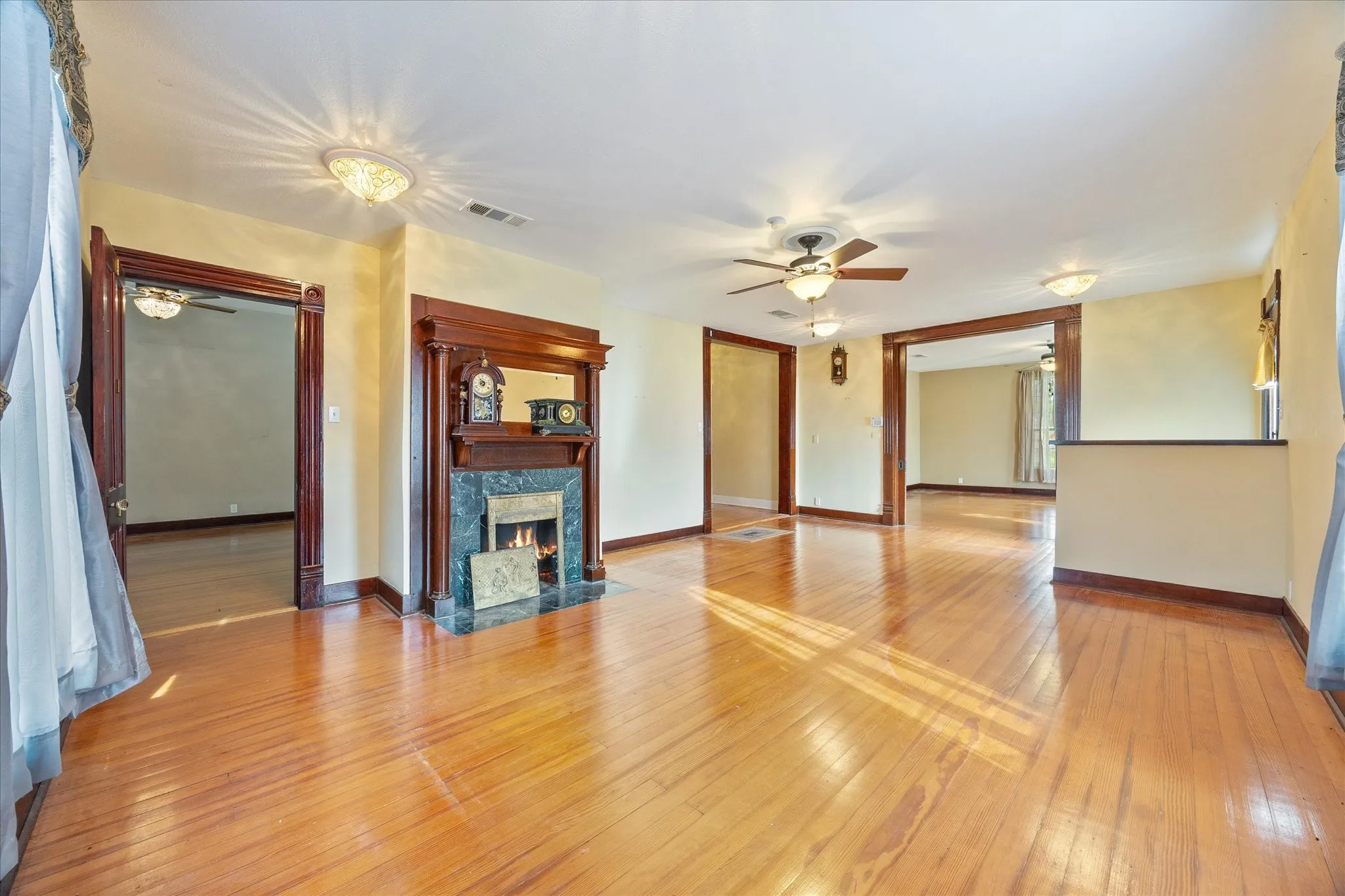Spacious interior featuring wood-finish flooring, a decorative fireplace with a dark stone surround, and multiple ceiling fans