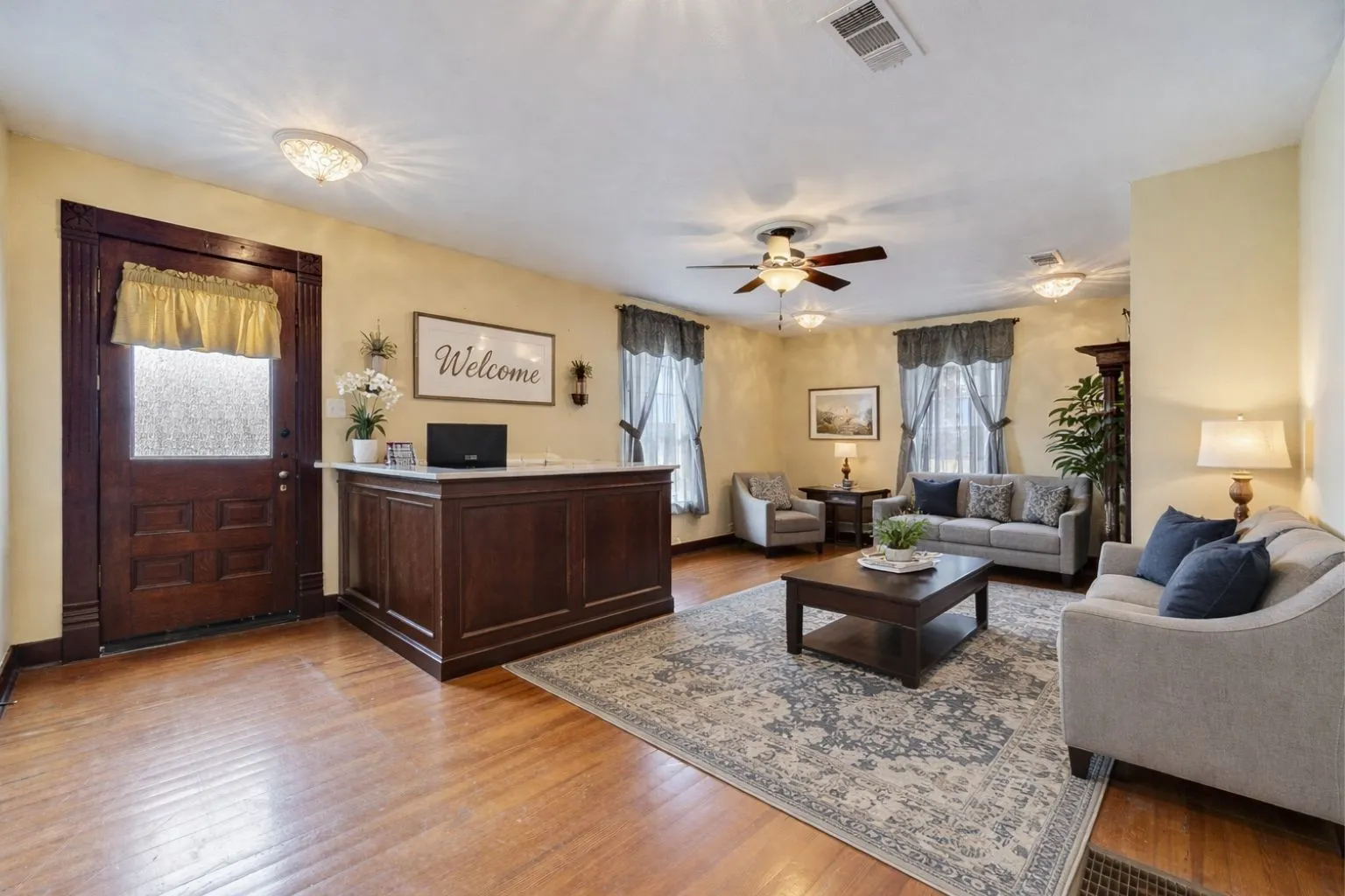 Hardwood-finish flooring throughout this open-concept room featuring a built-in reception desk with a light-toned countertop