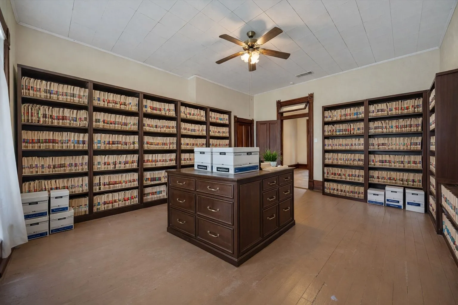Room featuring extensive built-in shelving, a central island with drawer storage, and a ceiling fan