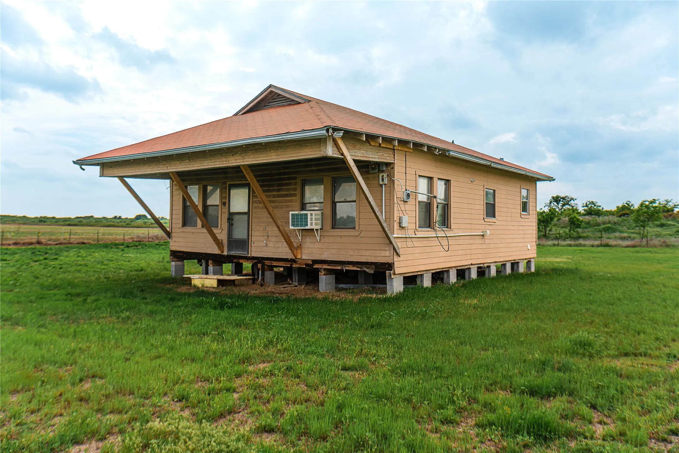 Elevated residence featuring a pitched roof, light-colored siding, and multiple windows