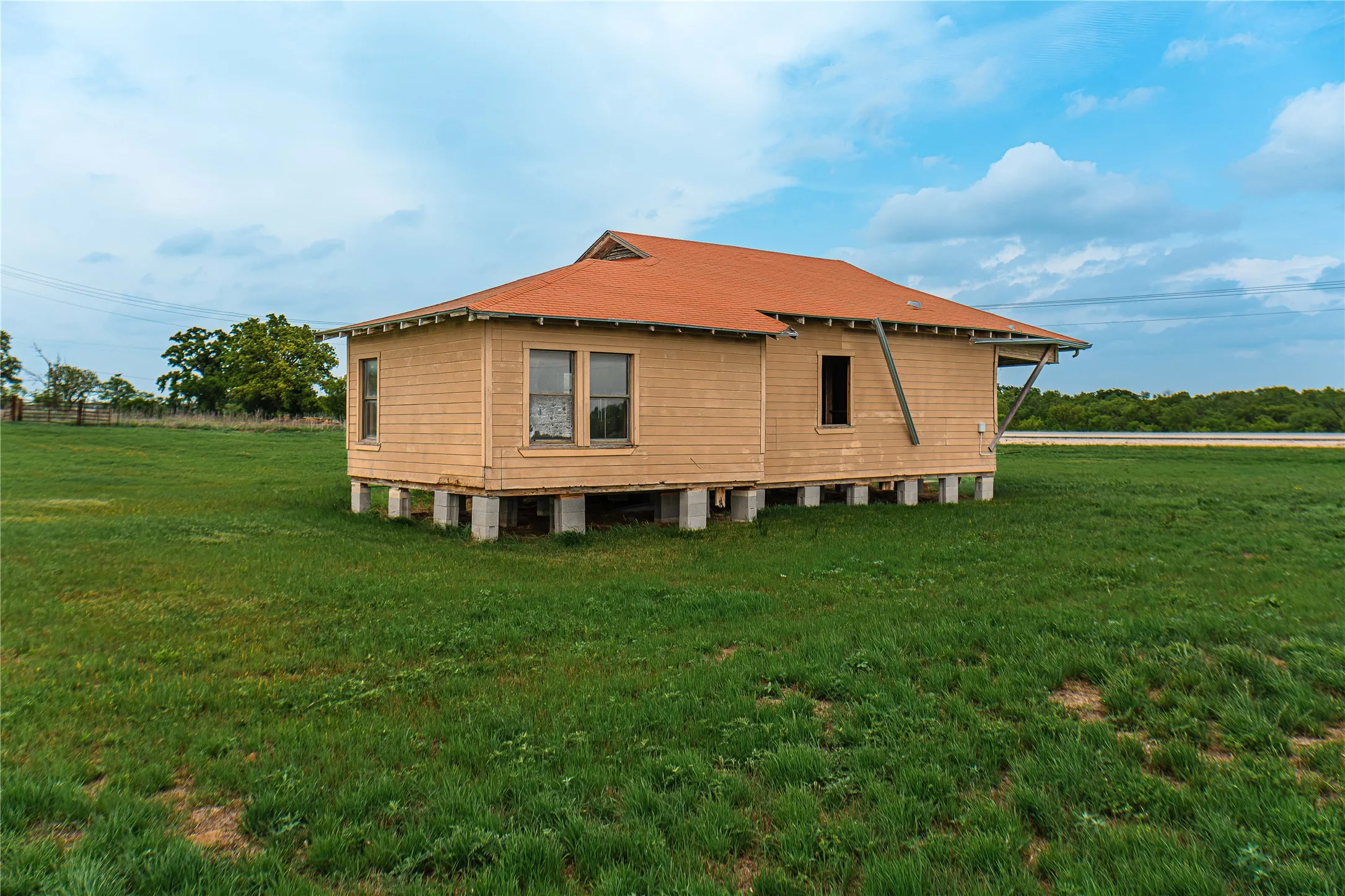 House on pier and beam foundation with horizontal siding and a red shingle roof