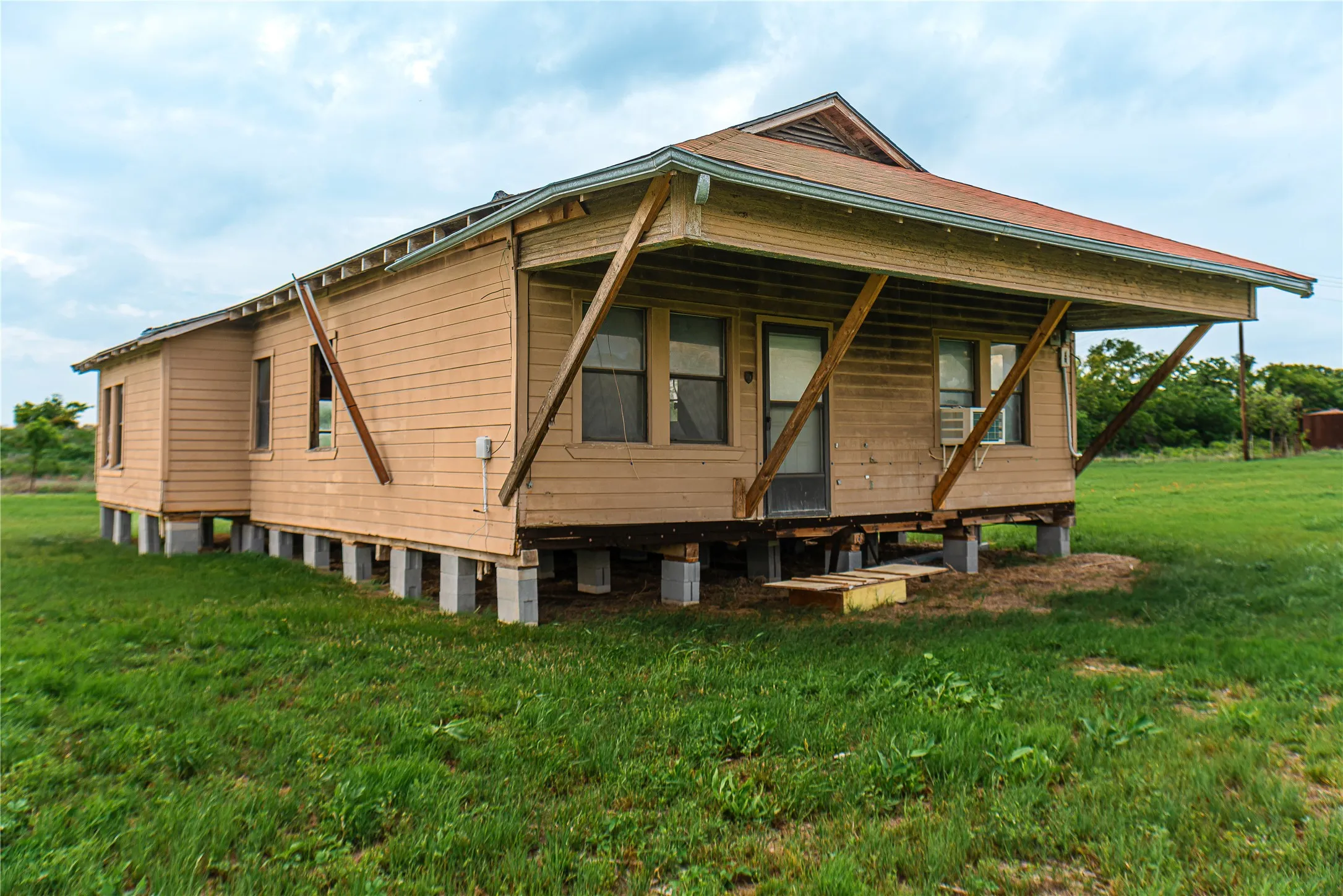 Single-story residence featuring light brown wood siding and a red shingle roof