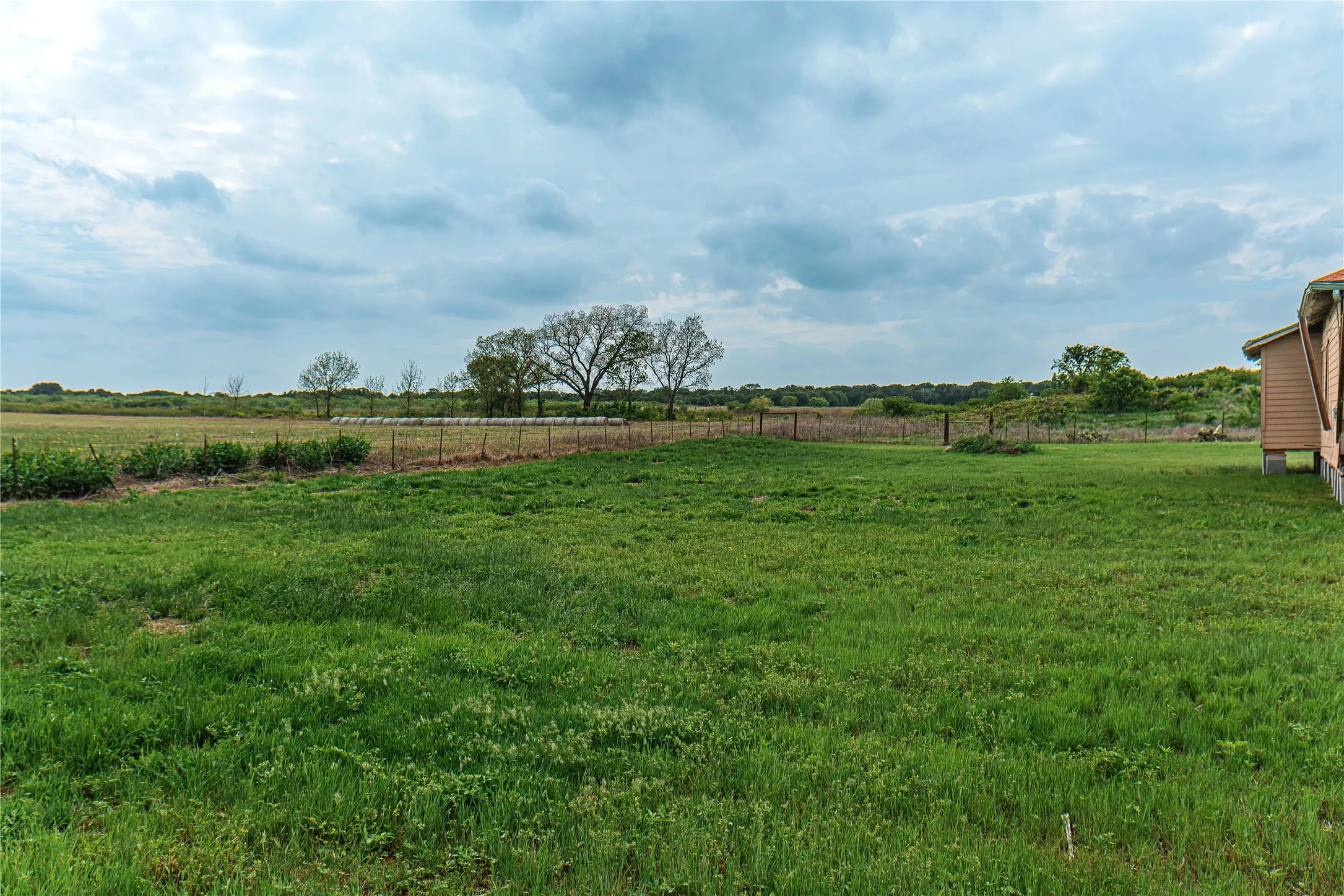 Expansive green lawn extending to a wire fence line