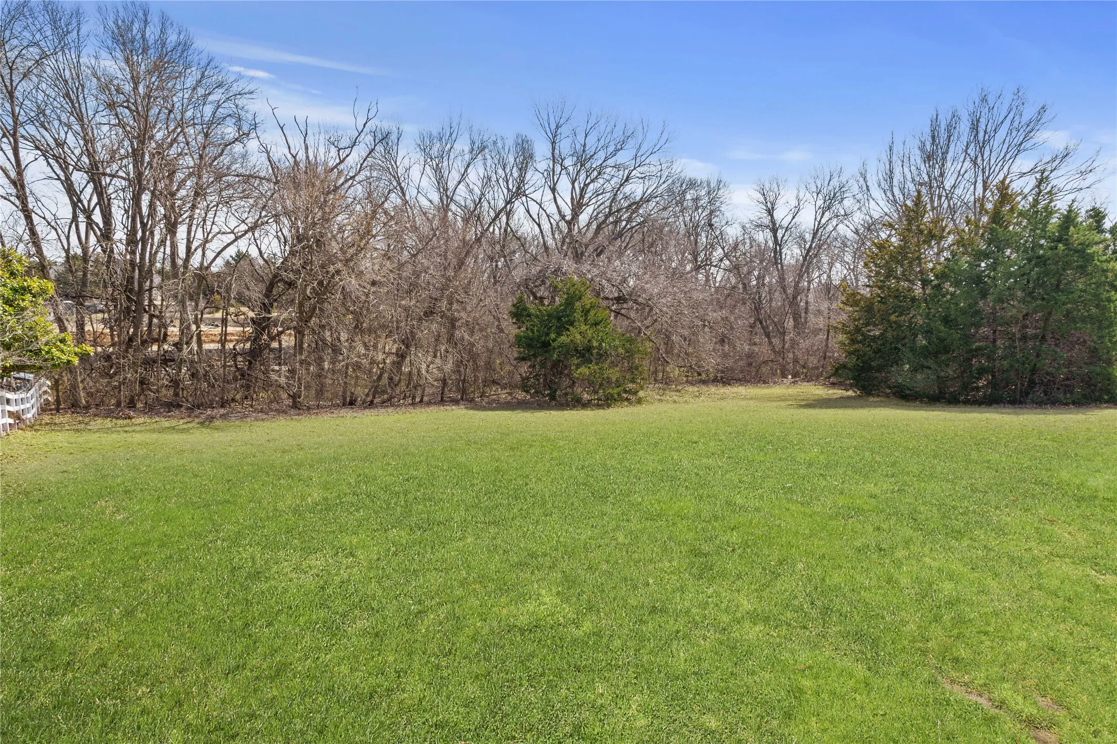 Expansive green lawn framed by mature trees and natural landscaping