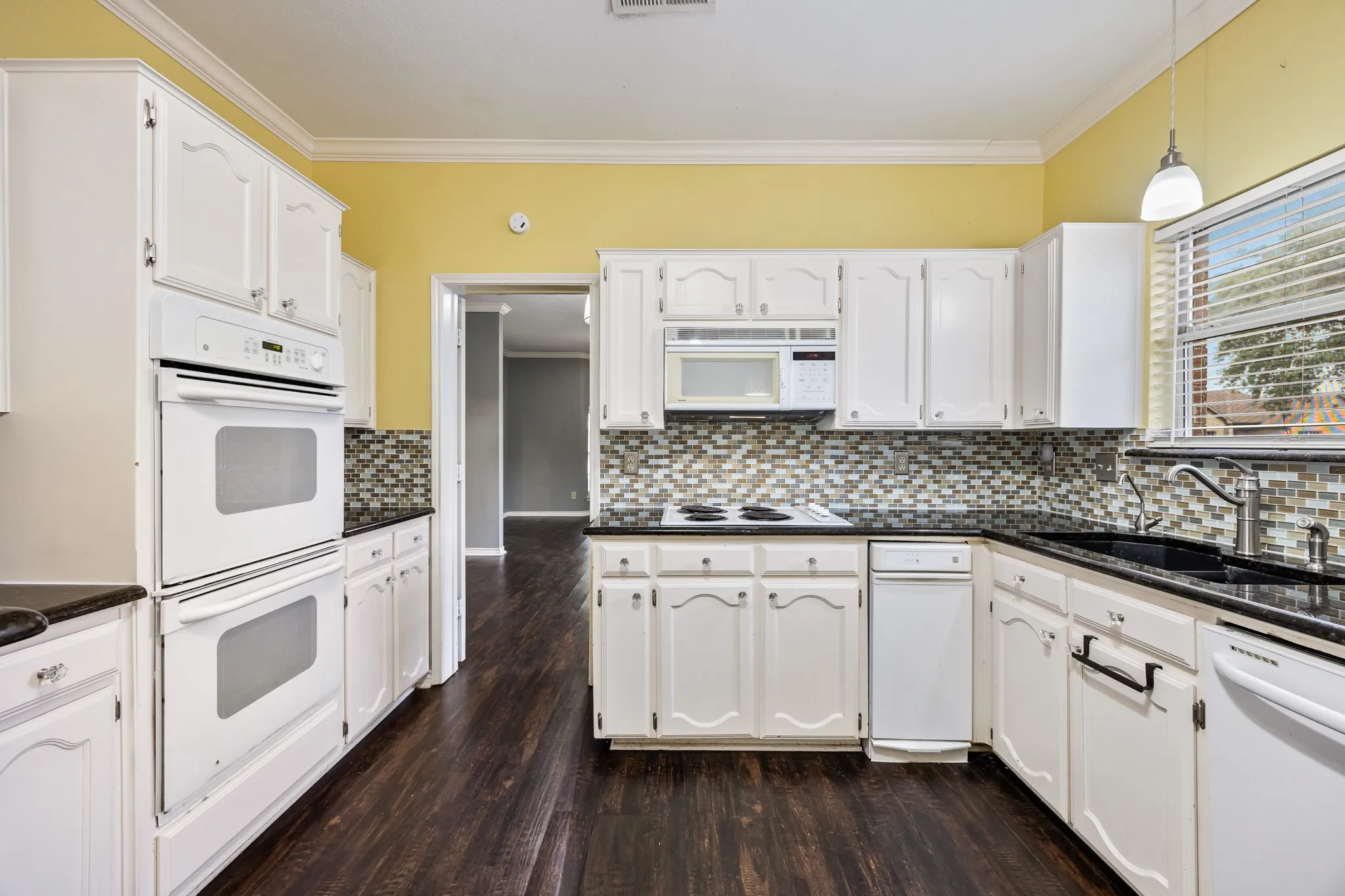 Kitchen with granite countertops, double oven and electric cooktop.