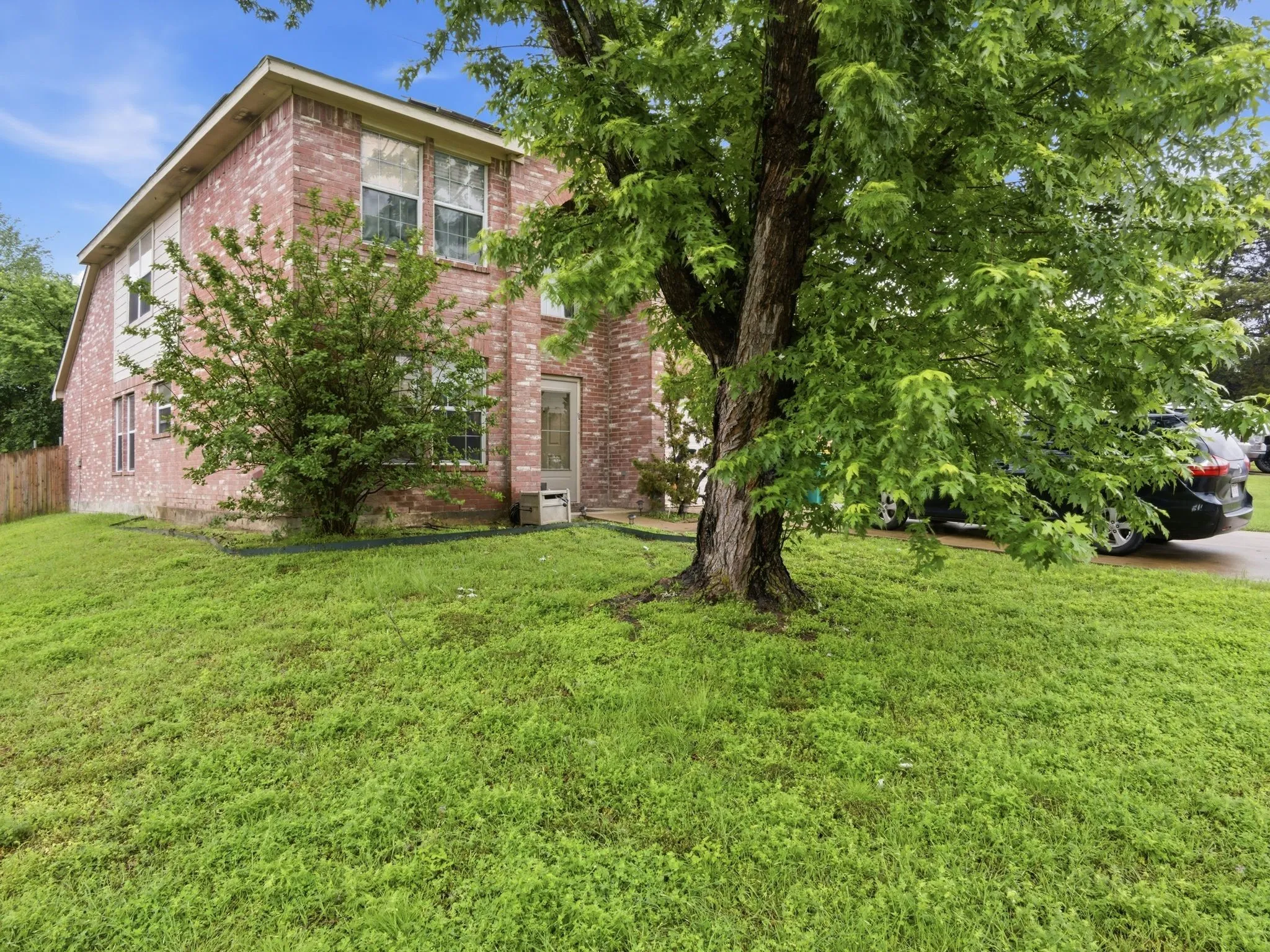 Brick exterior featuring multiple windows and a mature shade tree