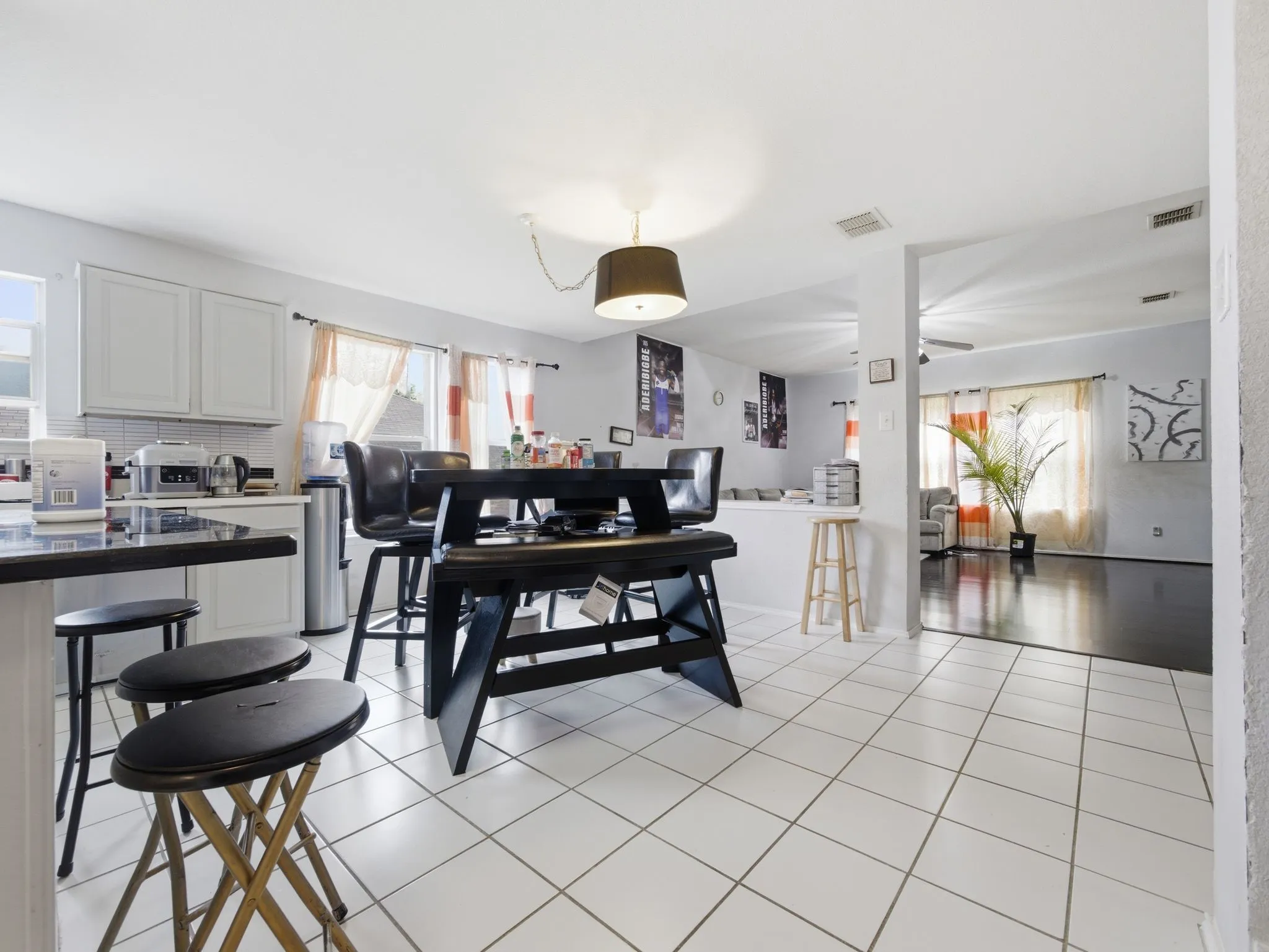 Kitchen featuring white tile flooring, white cabinetry, a dark countertop, and a contemporary pendant light fixture
