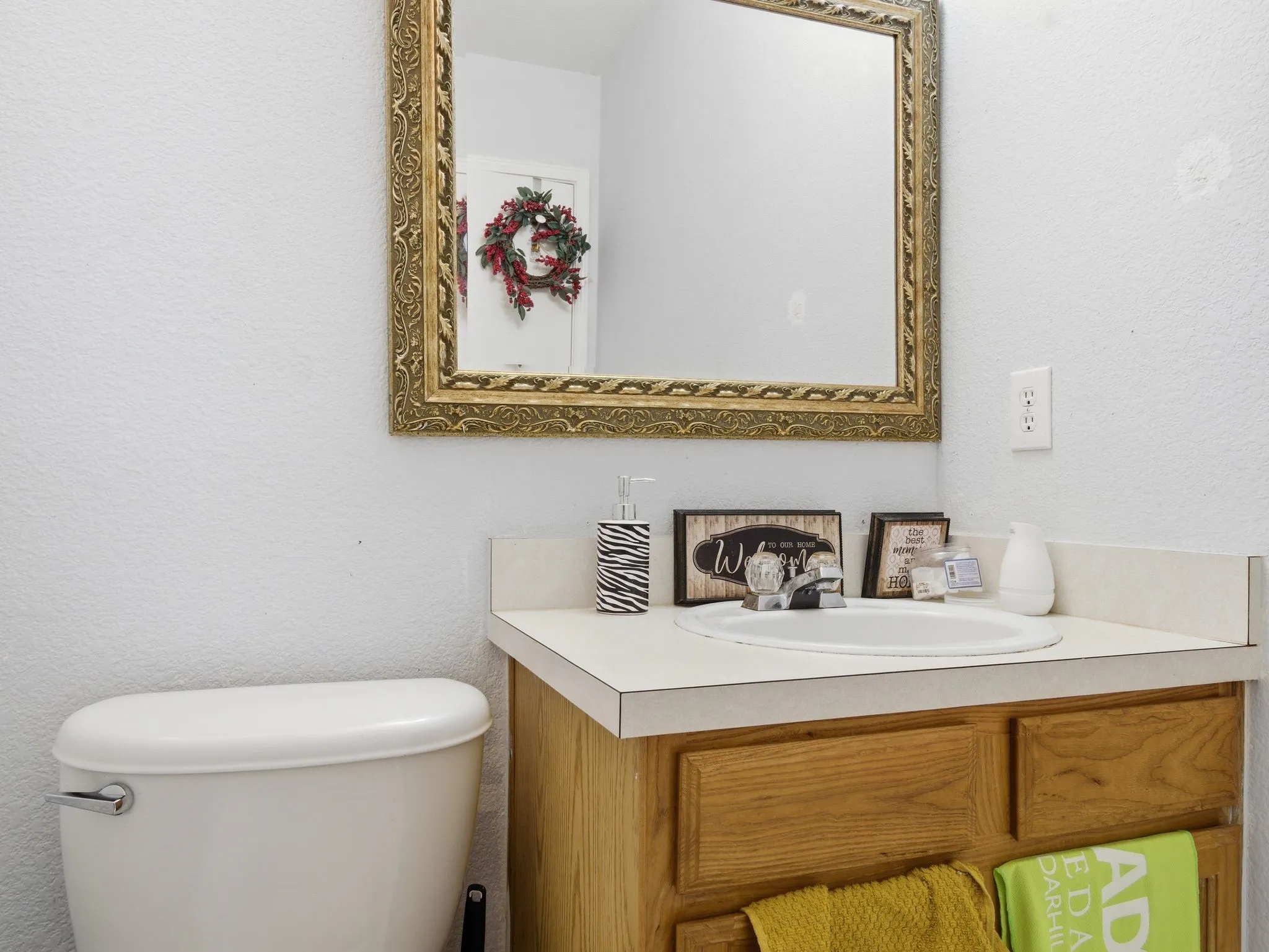 Bathroom featuring a white toilet, wood-finish vanity with a laminate countertop, and a decorative mirror